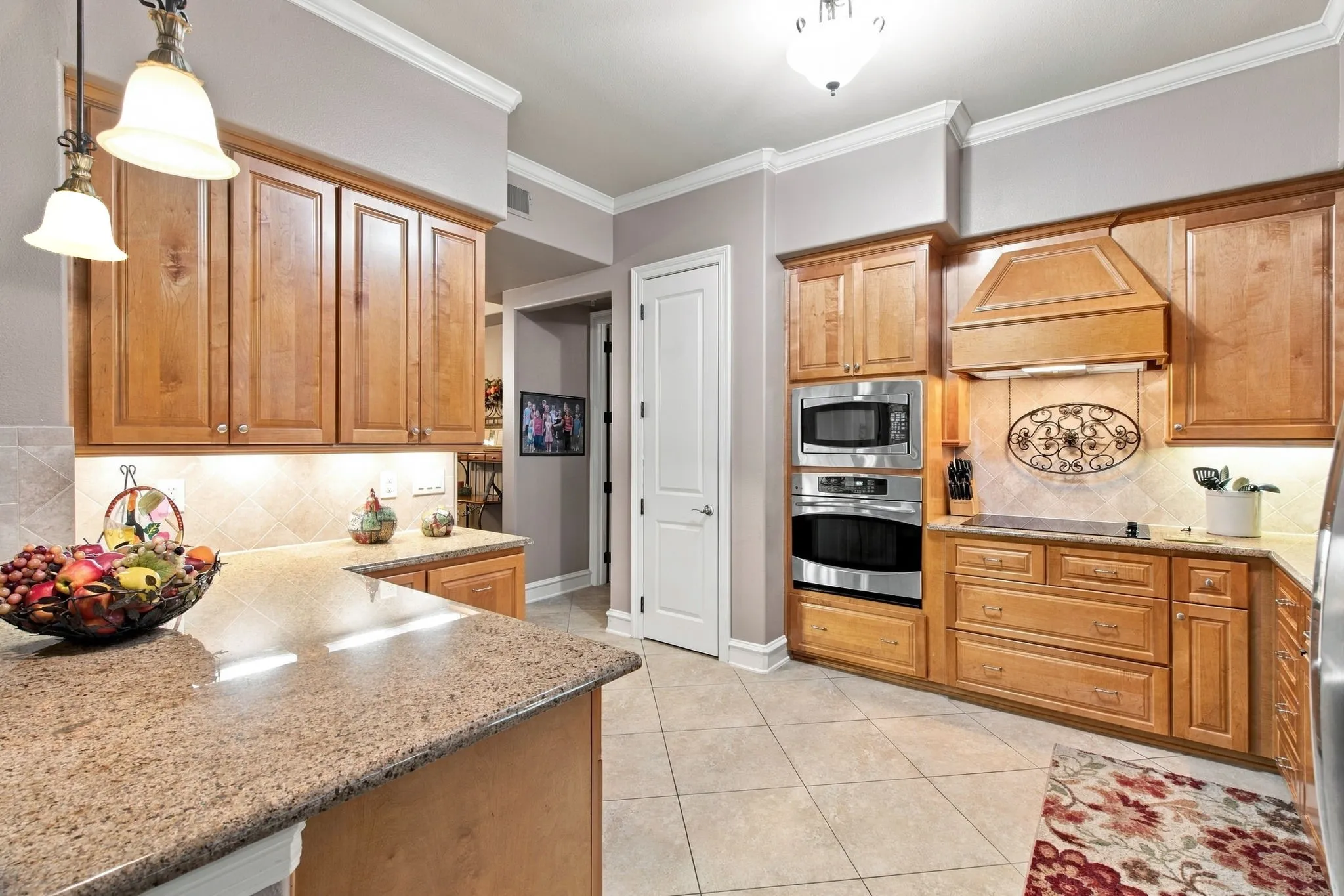 Kitchen featuring wood cabinetry, granite countertops, built-in stainless steel appliances, and a tiled backsplash