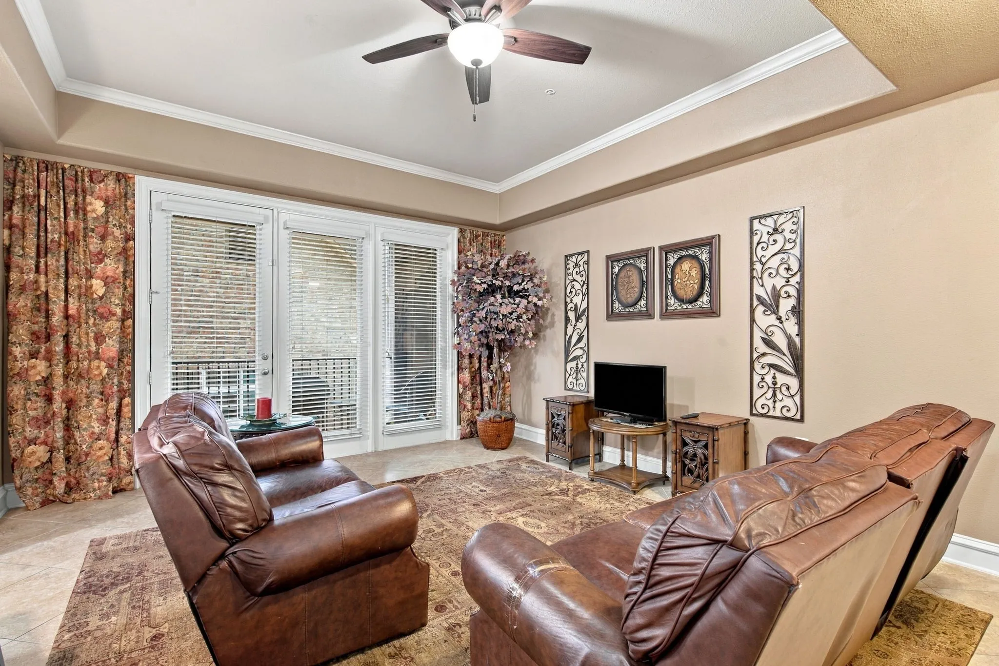 Recessed ceiling with crown molding, ceiling fan with light fixture, light-toned wall paint, and white framed glass doors with blinds