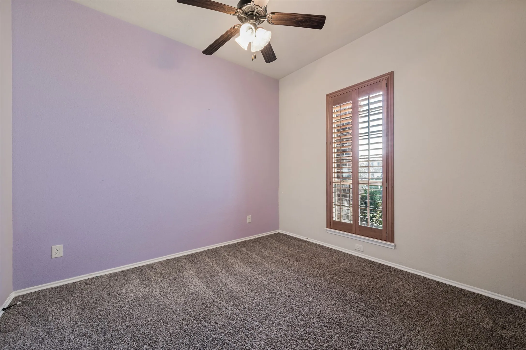Vaulted ceiling, ceiling fan with light fixture, carpeted flooring, and window with wood plantation shutters