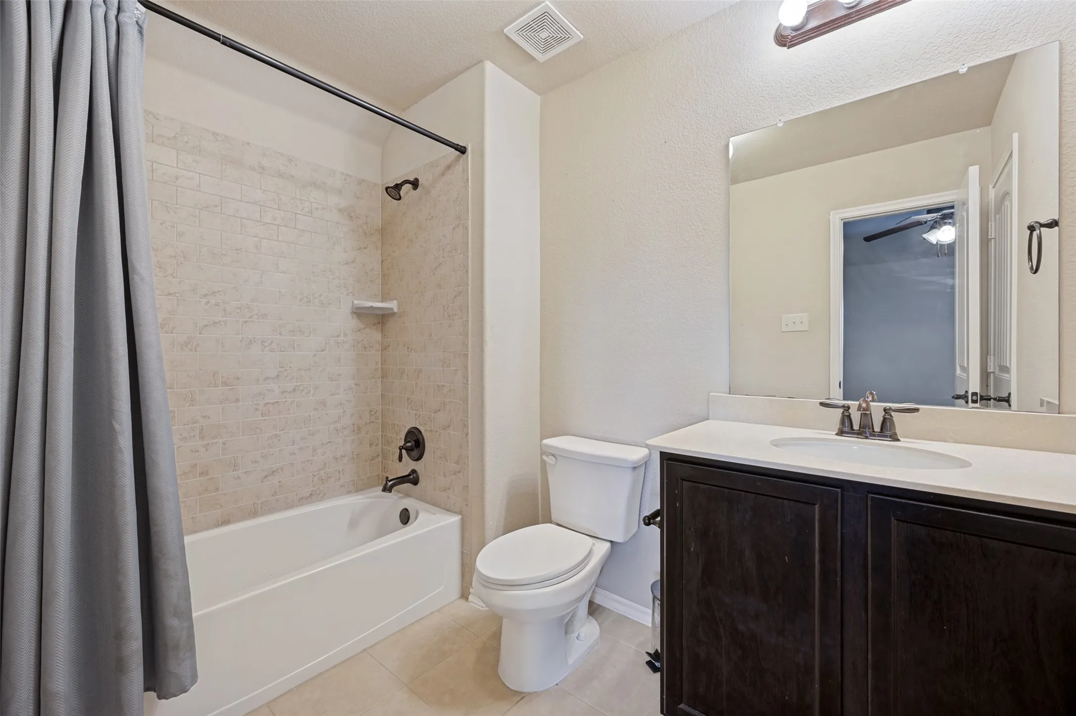 Bathroom featuring a shower/tub combination with subway tile surround, dark wood-finish vanity with countertop, and an integrated sink