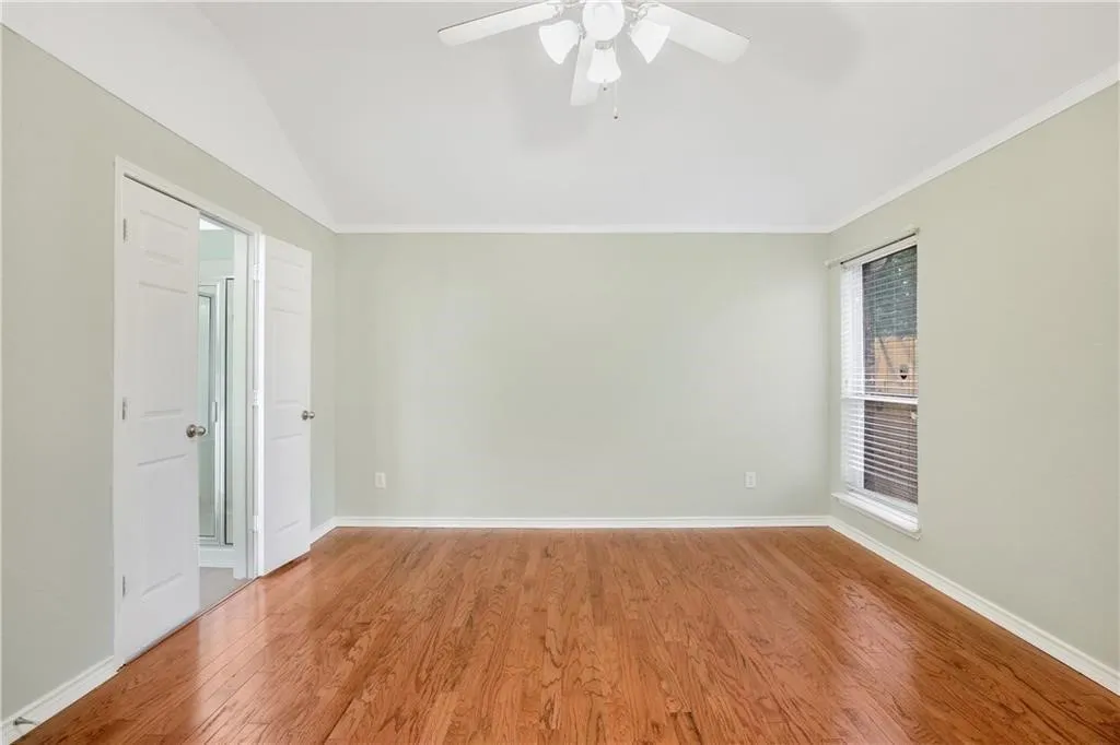 Vaulted ceiling with a ceiling fan, wood-finish flooring, and a window with blinds