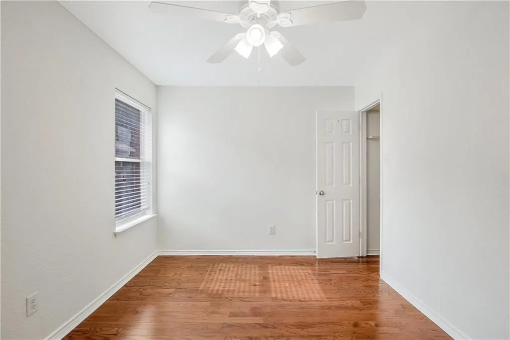 Hardwood flooring, ceiling fan with integrated lighting, window with blinds, paneled door, and closet space