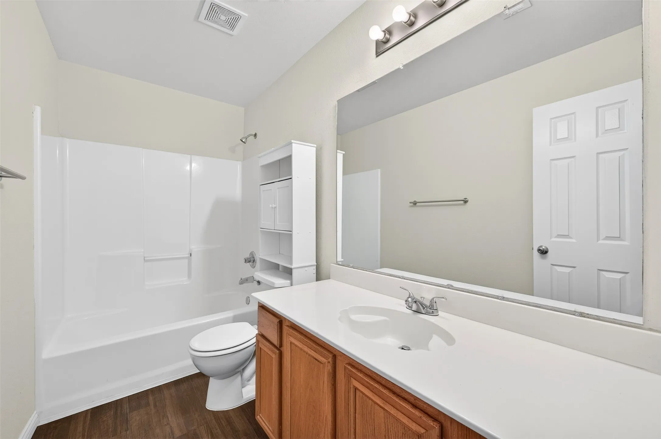 Wood-finish LVP flooring with a white tub and shower combo