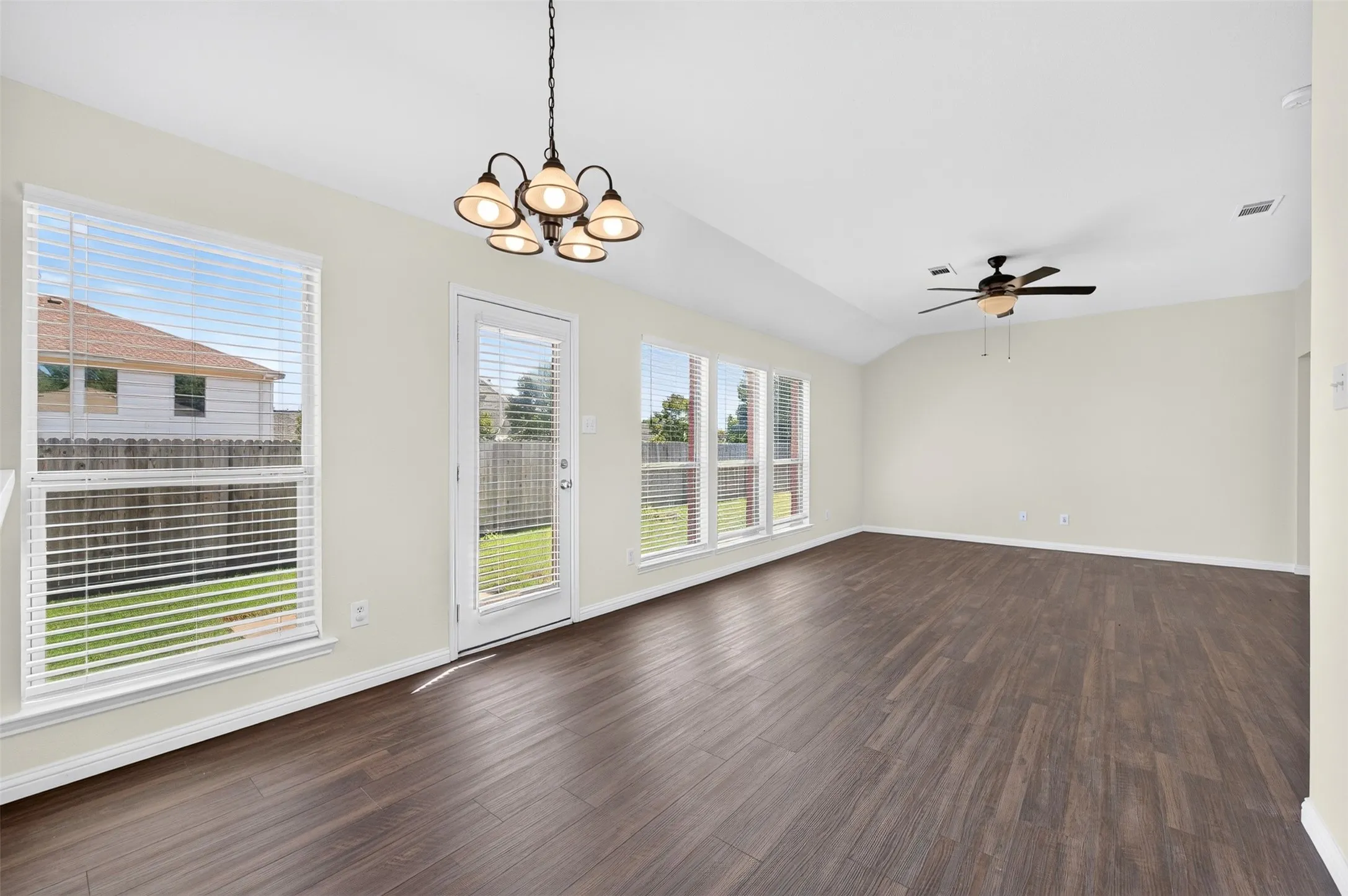 Dining and living areas with a ceiling fan, easy care LVP flooring, multiple windows, and a glass-paneled back door