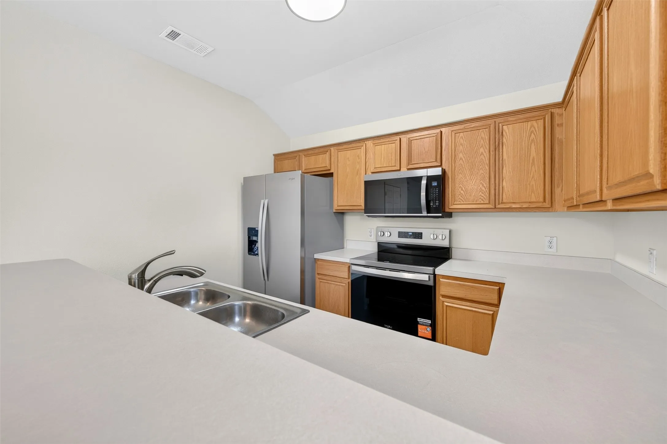 Kitchen featuring new stainless steel appliances, light wood-finish cabinetry, a double basin sink