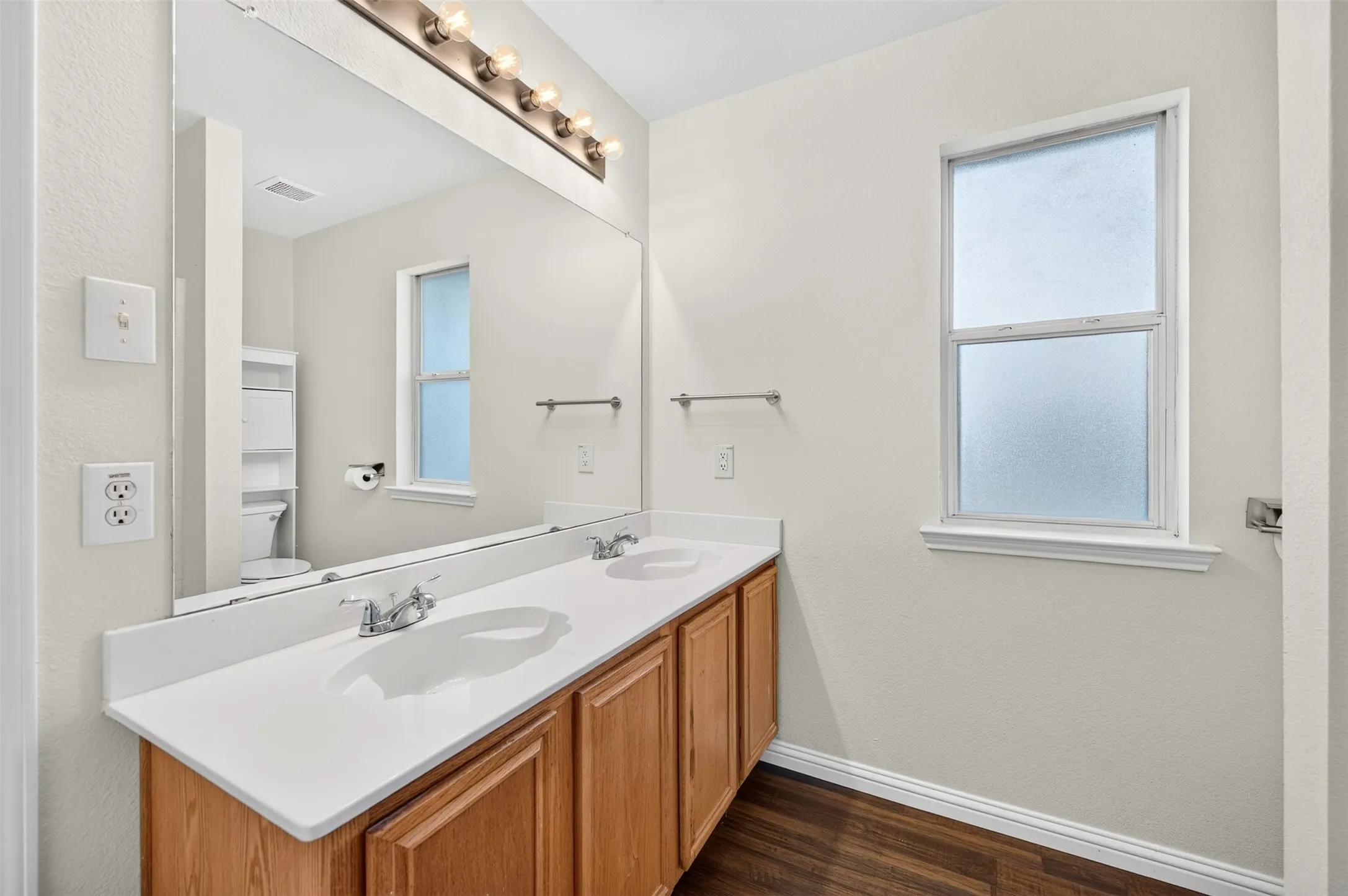 Double vanity with white countertops, wood-finish vanity cabinet and chrome fixtures