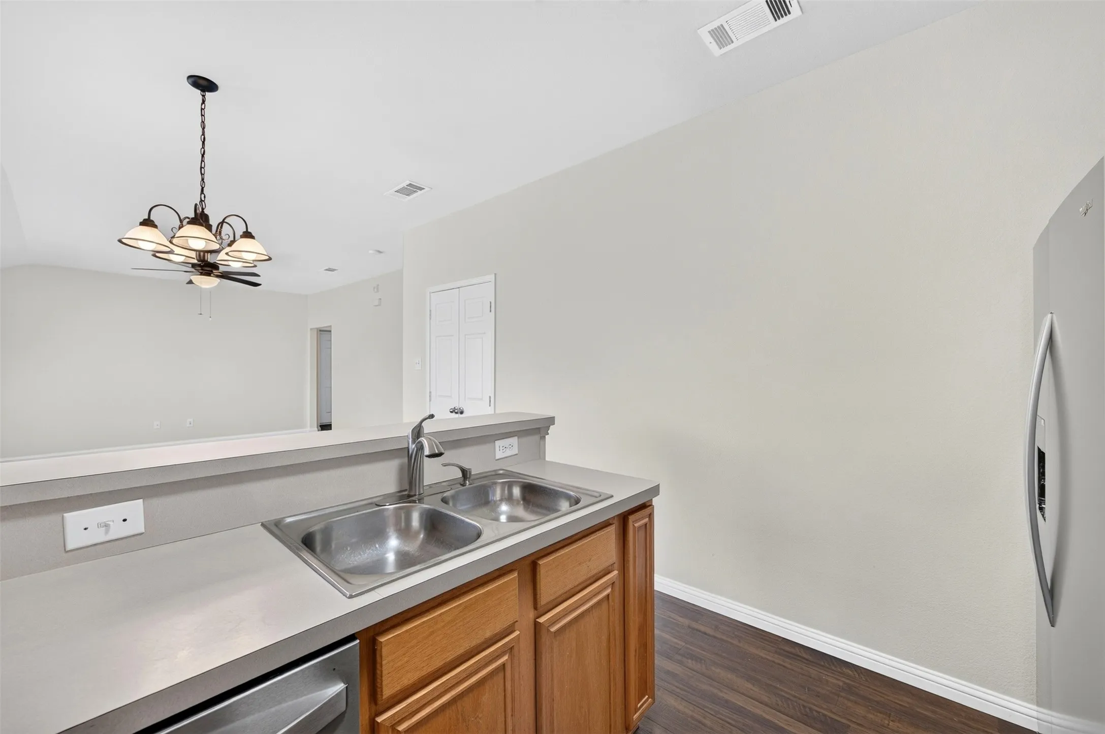 Stainless steel double basin sink, chrome faucet, dishwasher and light wood-finish cabinetry.