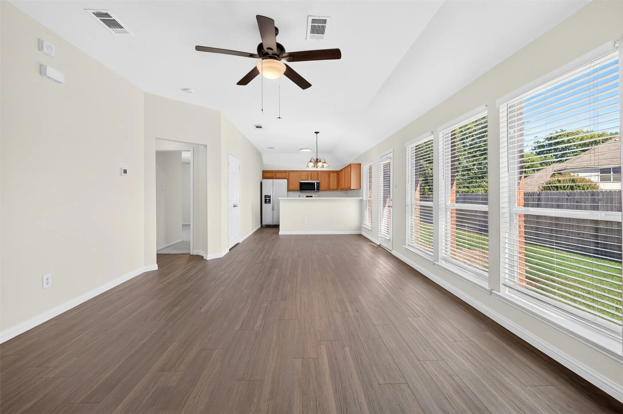 Open-concept living, dining space featuring wood-finish flooring, a ceiling fan, and multiple windows