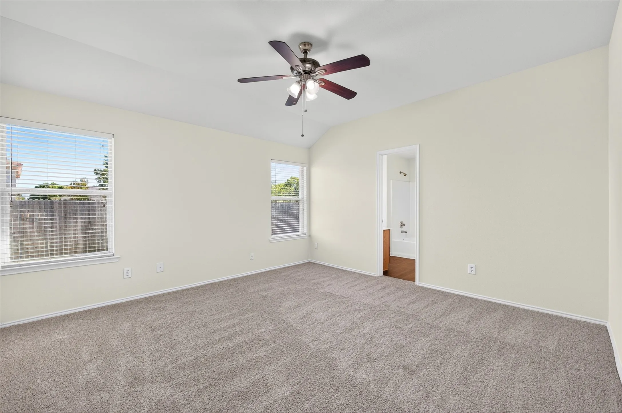 Two windows, looking to fenced backyard, ceiling fan and new neutral carpeting