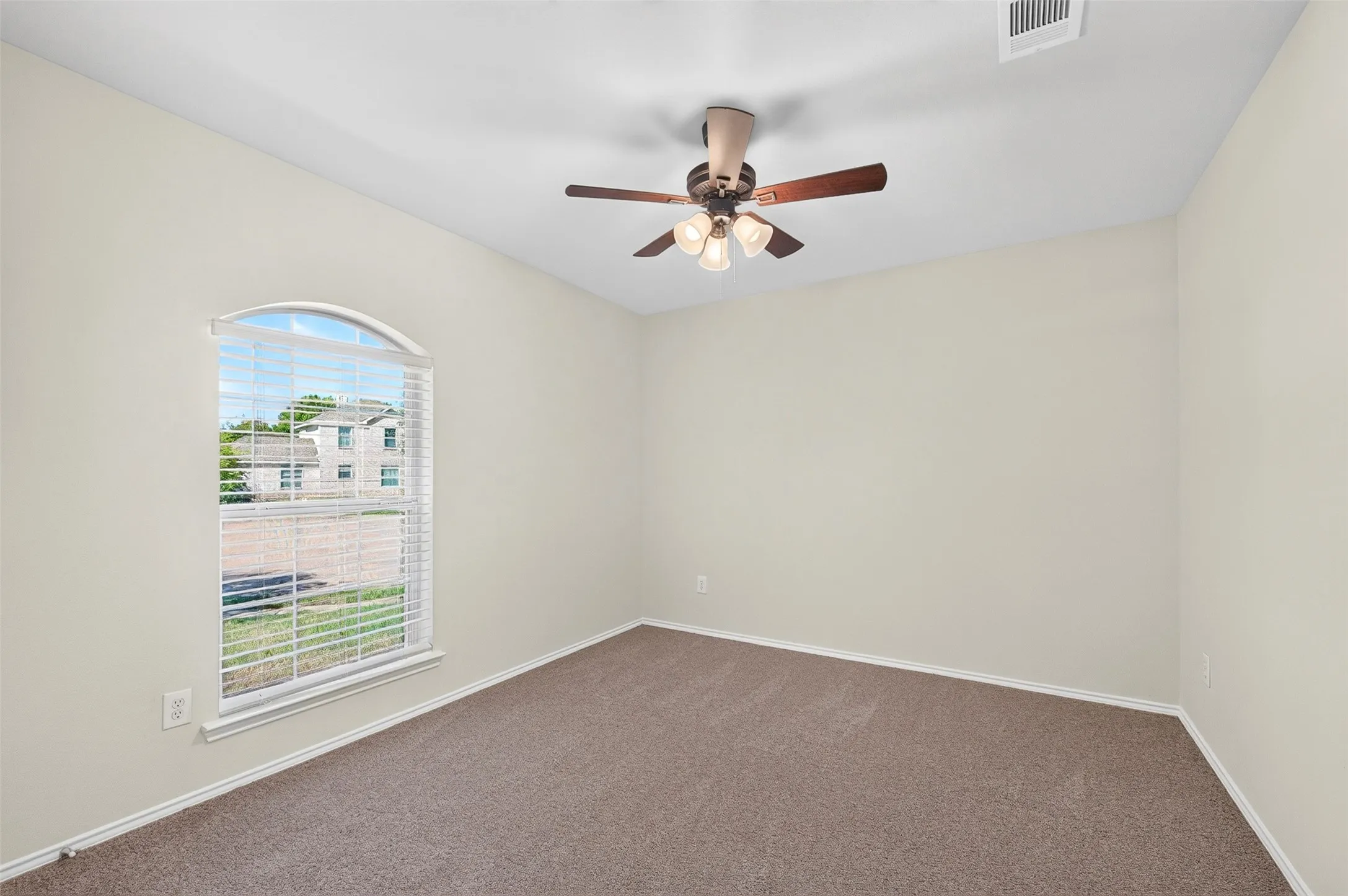 Arched window with blinds, ceiling fan with integrated lighting, and fresh neutral carpeting
