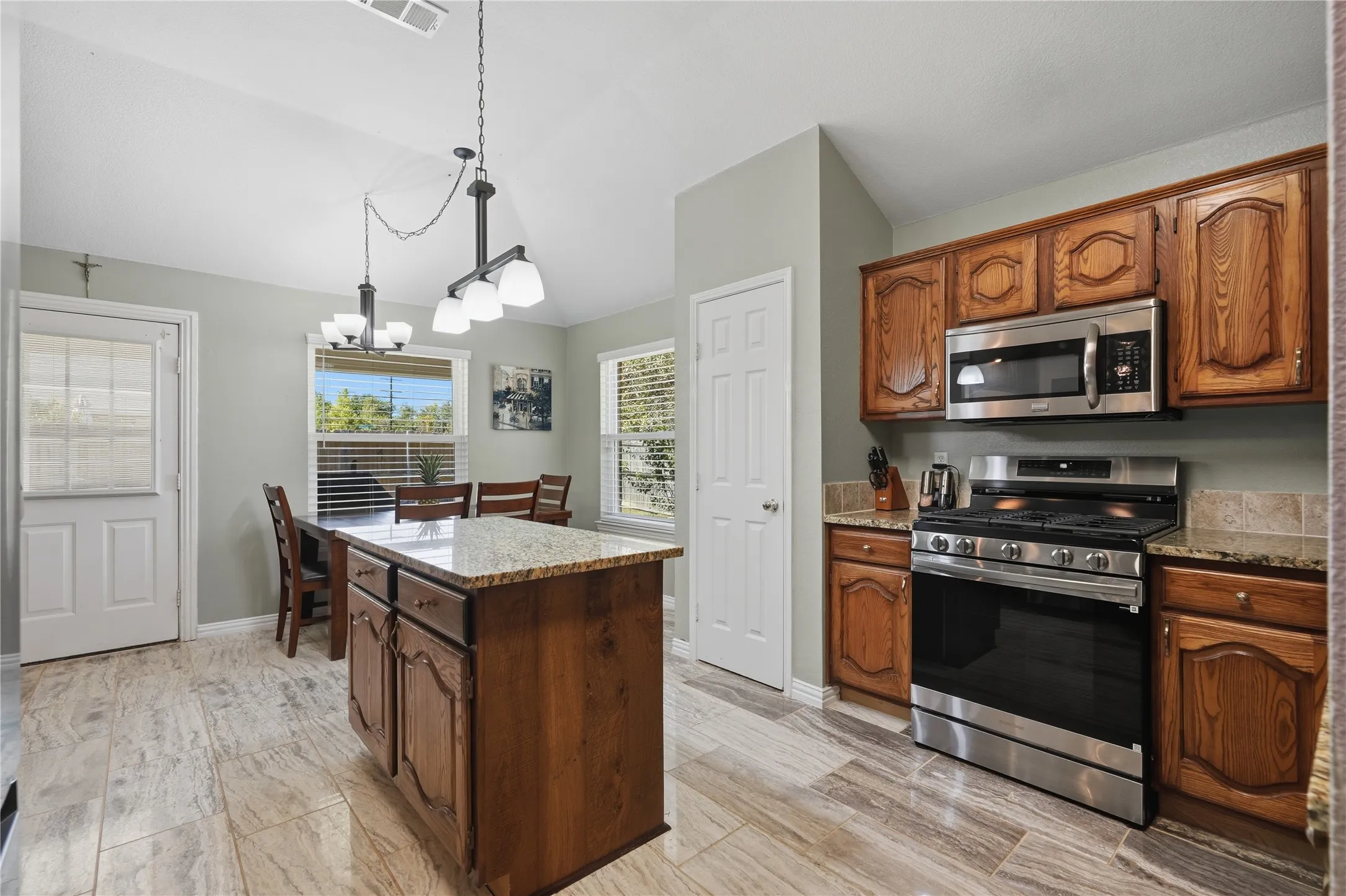 Kitchen featuring wood-finish cabinetry, stainless steel appliances, granite countertops, and wood-look tile flooring