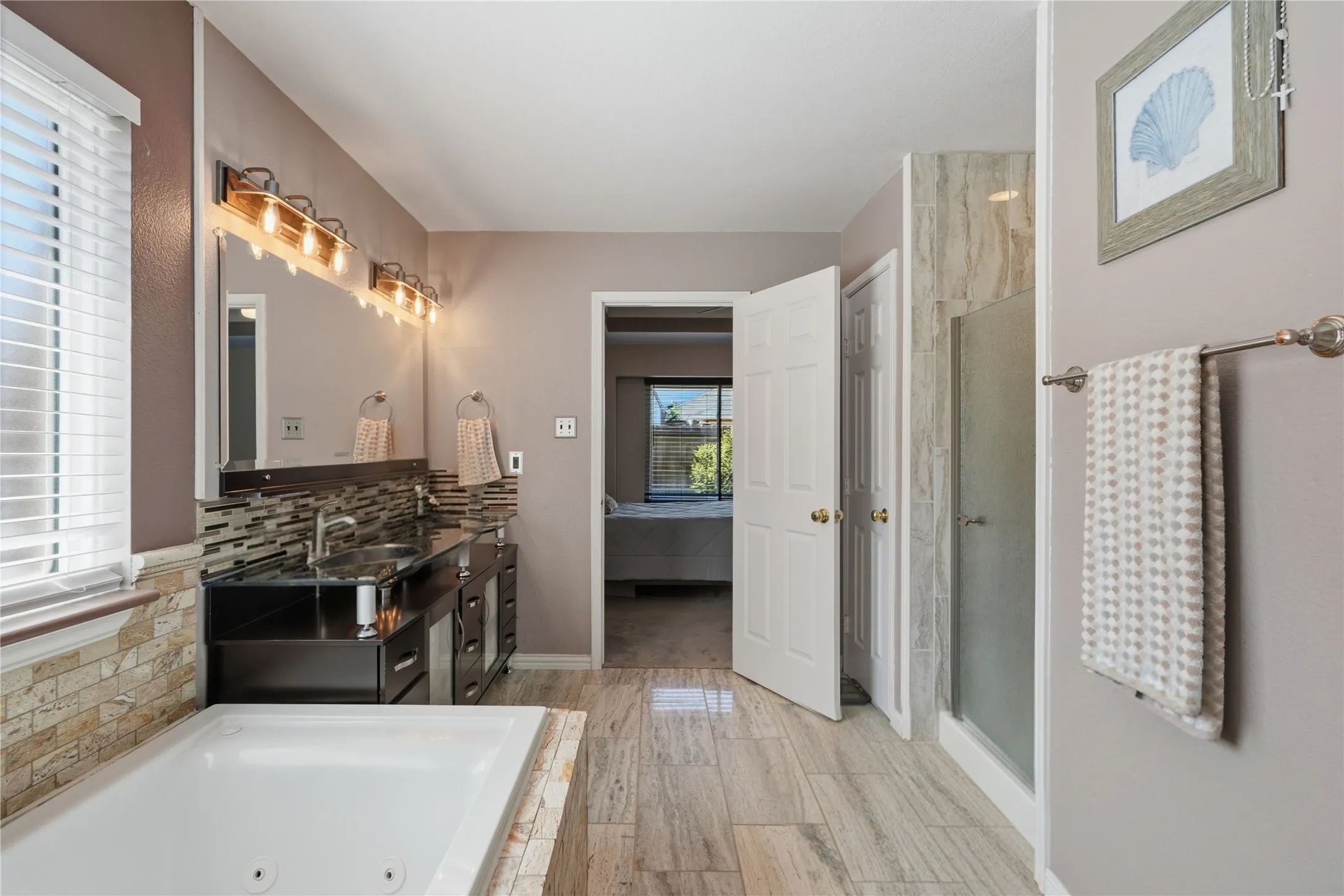 Spacious bathroom featuring a soaking tub, dual vanity with undermount sinks, and a glass-enclosed shower