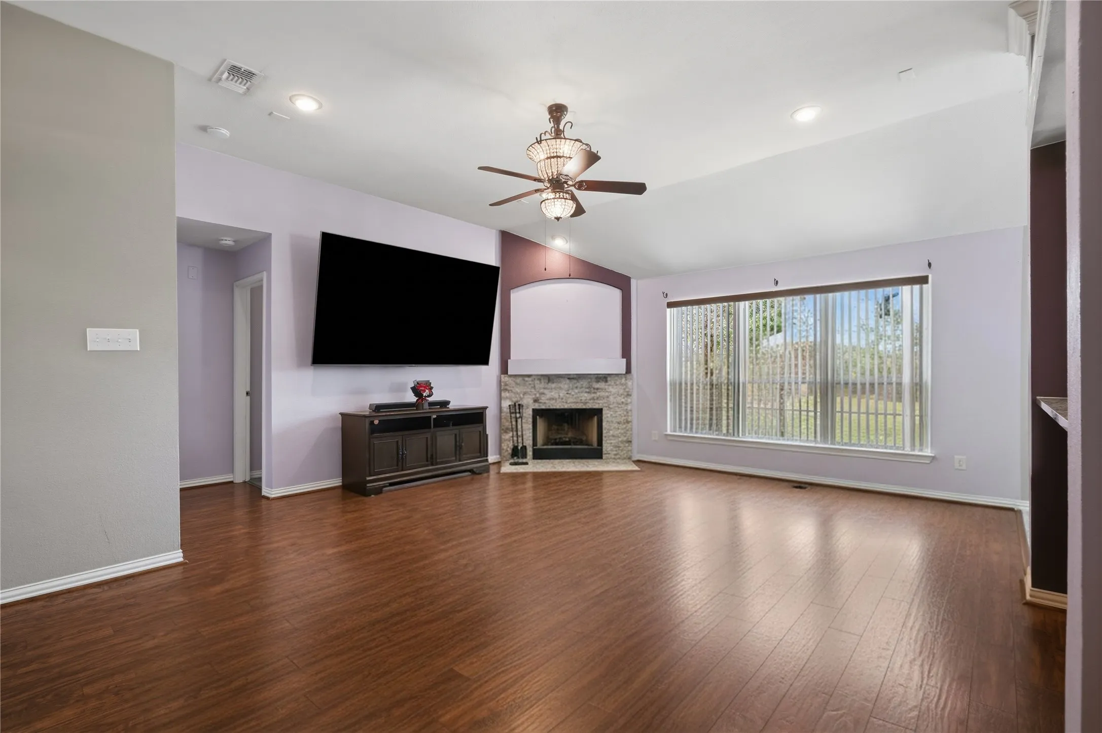 Wood-finish flooring throughout, vaulted ceiling, recessed lighting, ceiling fan with light fixture, and stone-faced fireplace