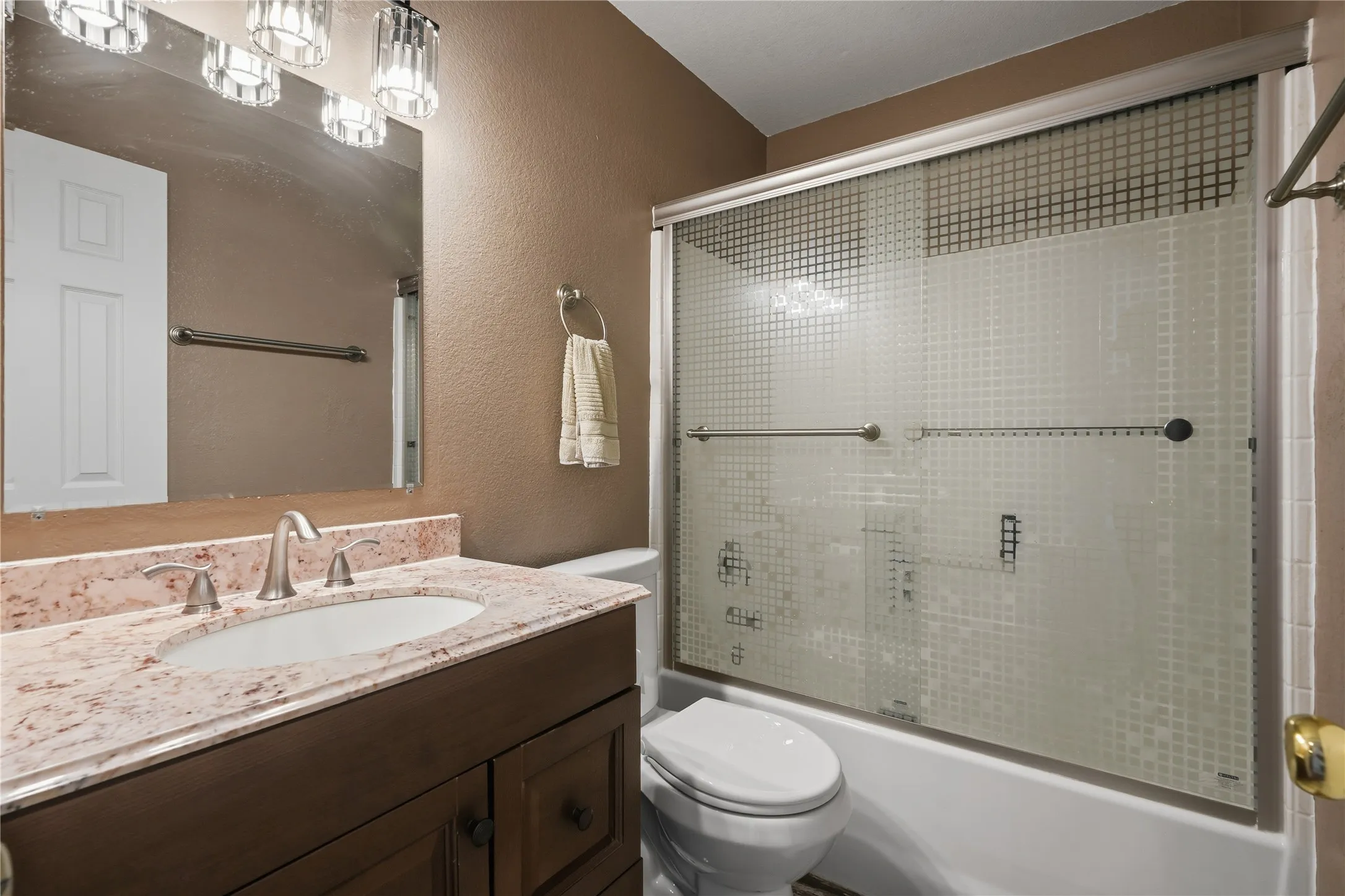 Brown wood-finish vanity with an undermount sink, a light-colored stone countertop, and a brushed nickel faucet