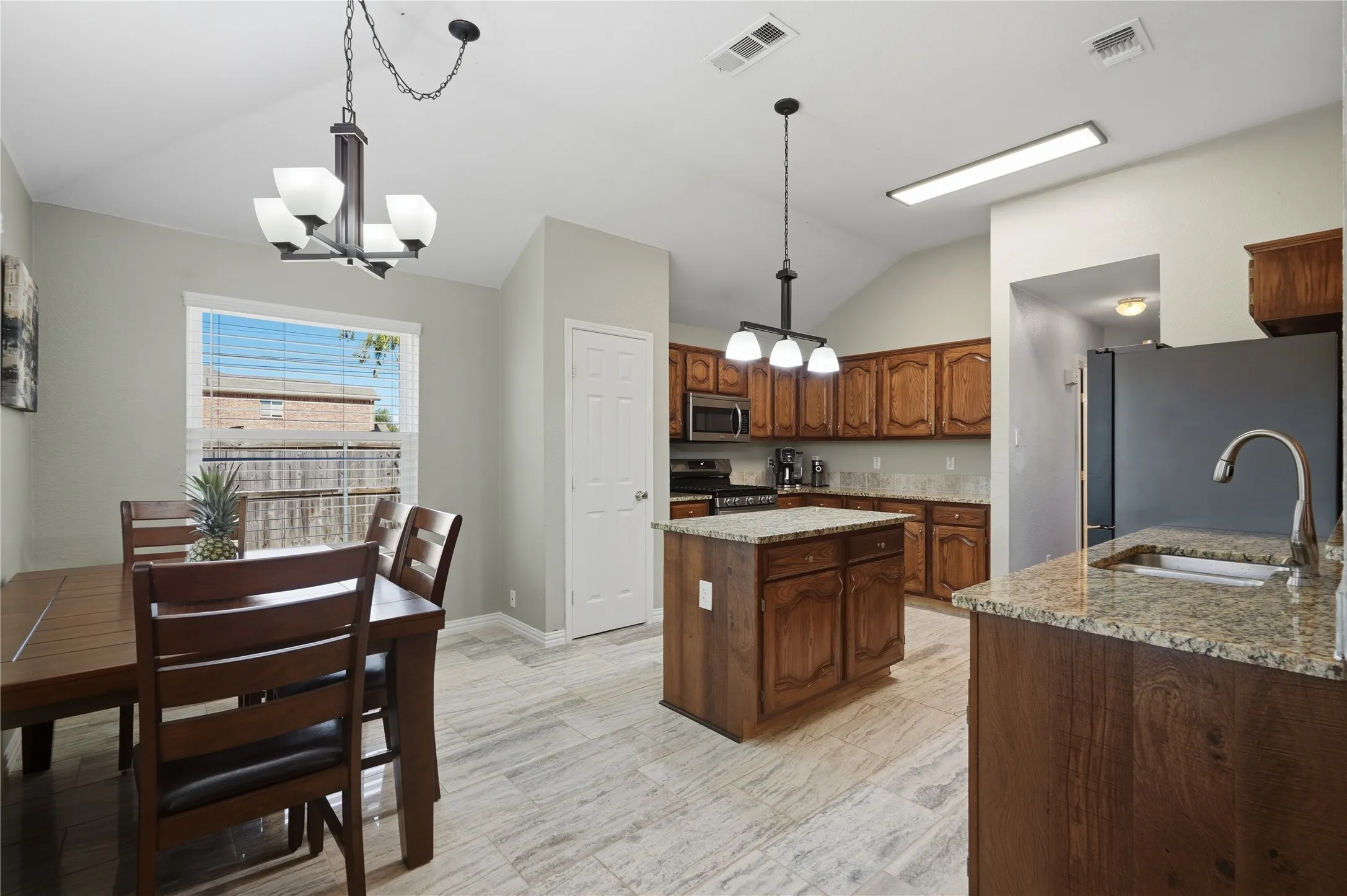 Vaulted ceiling, recessed lighting, wood-finish cabinetry, granite countertops, and tile flooring