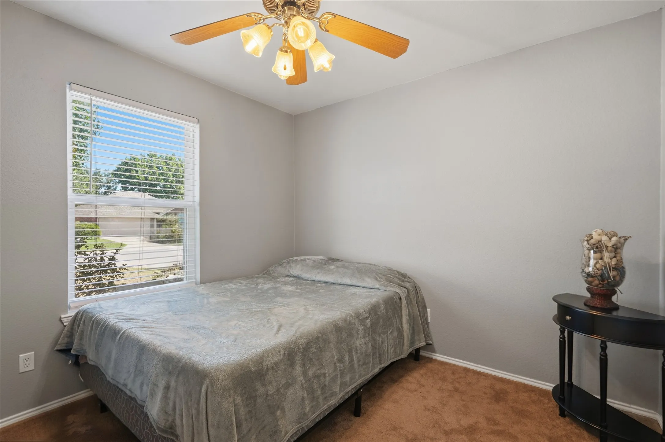 Neutral wall paint, window with blinds, ceiling fan with light fixture, and brown carpeting