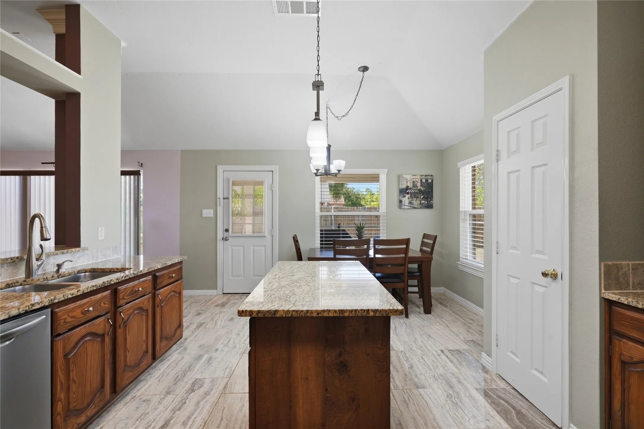 Kitchen featuring wood cabinetry, granite countertops, a stainless steel sink, and wood-finish flooring