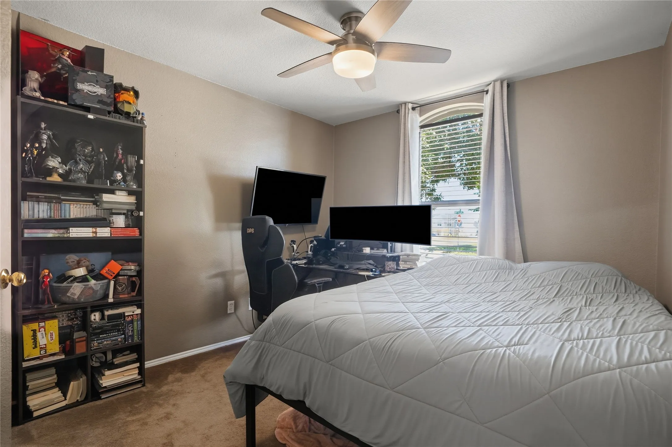 Recessed window with blinds, ceiling fan with integrated lighting, wall-mounted television, and brown carpeting