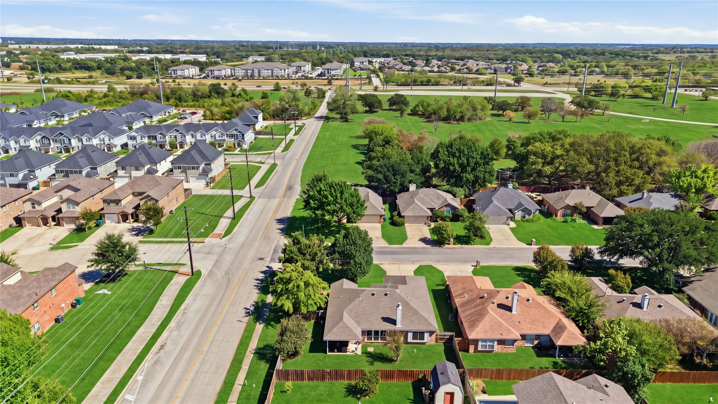 Aerial perspective showcasing residential properties with varied rooflines and a mix of mature and newly planted trees