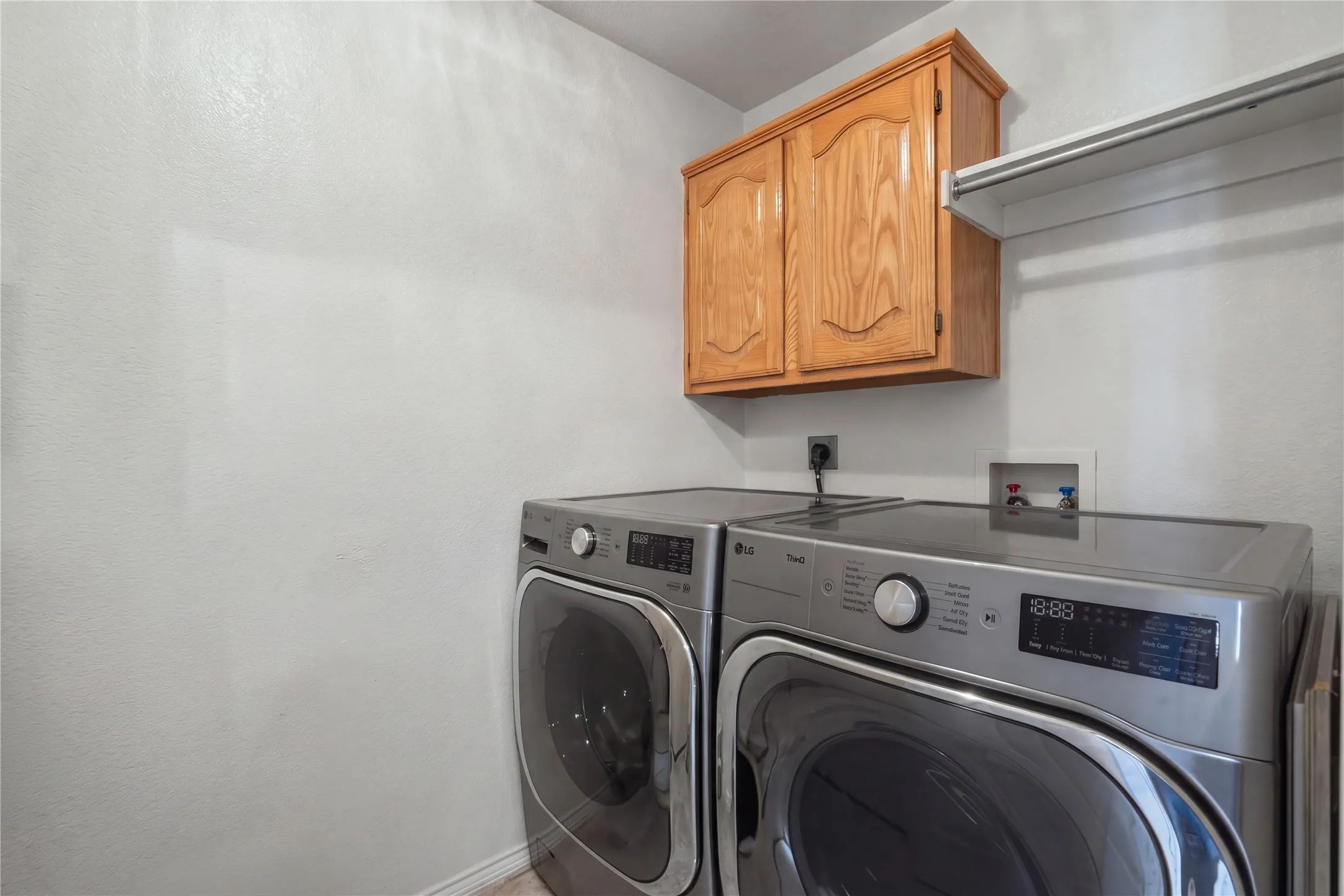 Laundry area with wood cabinetry and an integrated storage shelf