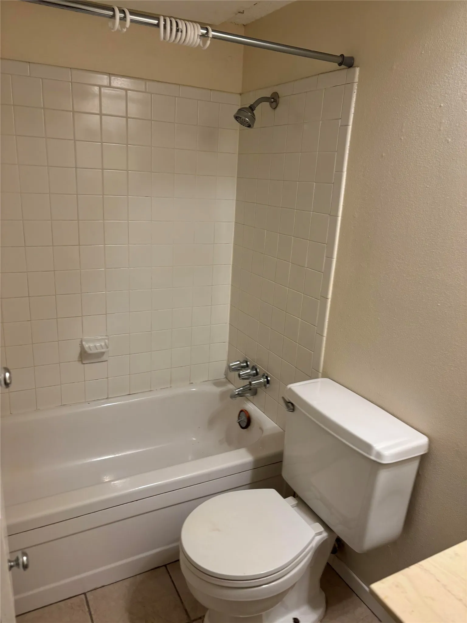 Bathroom with tile floors, toilet, and tiled shower / bath combo
