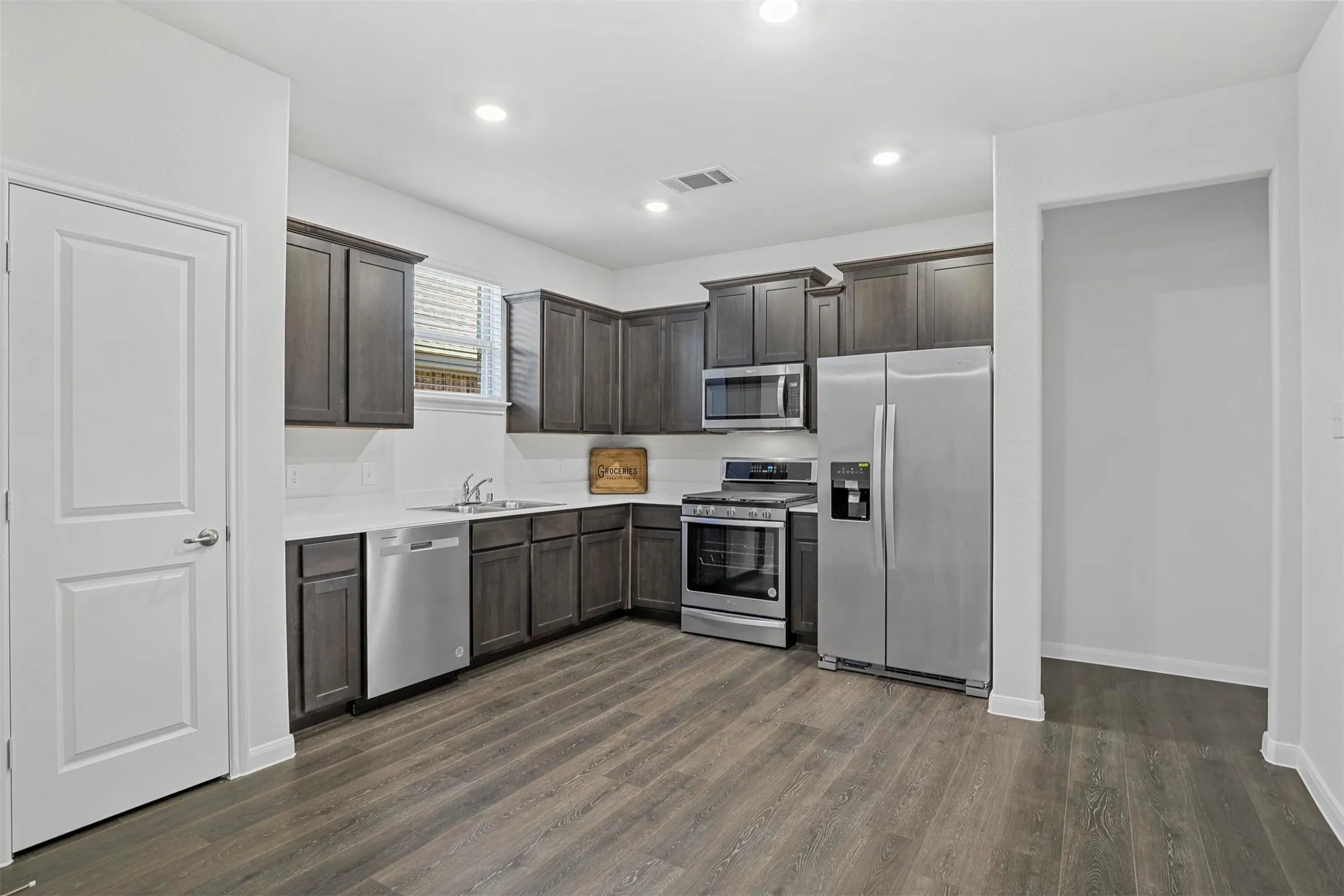Modern kitchen featuring wood-finish flooring, dark wood cabinetry, stainless steel appliances, and recessed​​‌​​​​‌​​‌‌​‌‌​​​‌‌​‌​‌​‌​​​‌​​ lighting