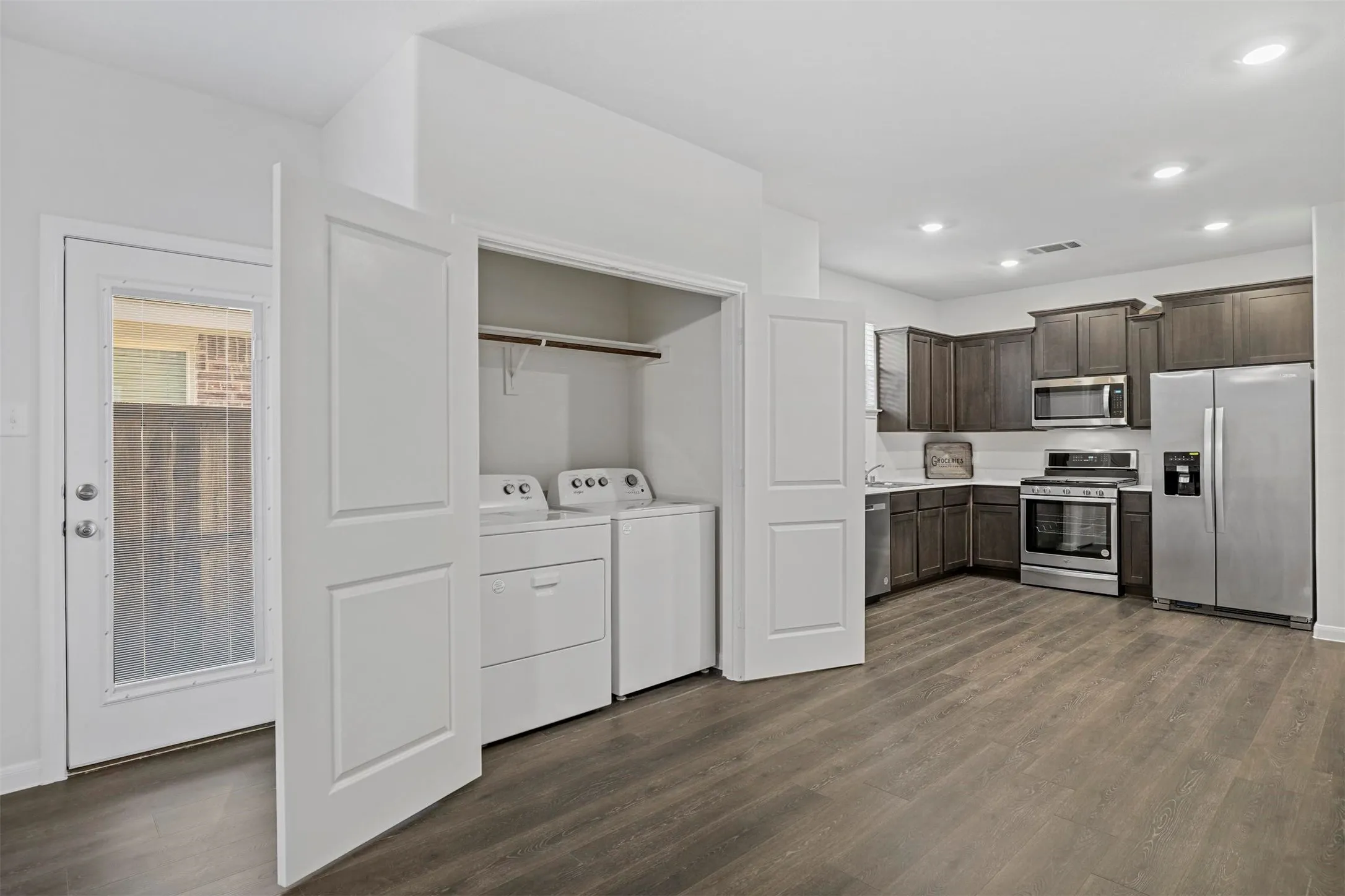 Kitchen featuring dark wood-finish cabinetry, stainless steel appliances, and wood-finish flooring