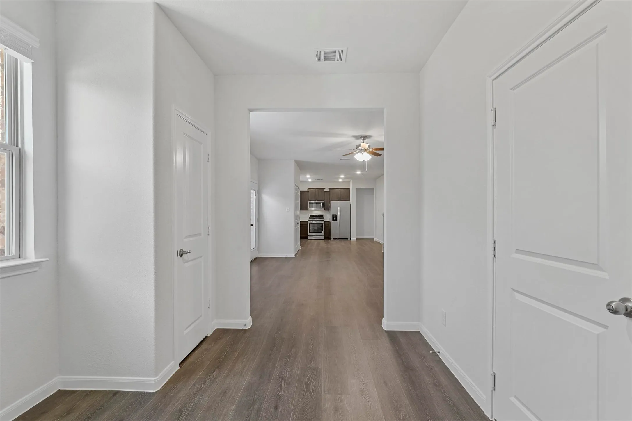 Wood-finish flooring throughout, white interior doors, and a window with white trim