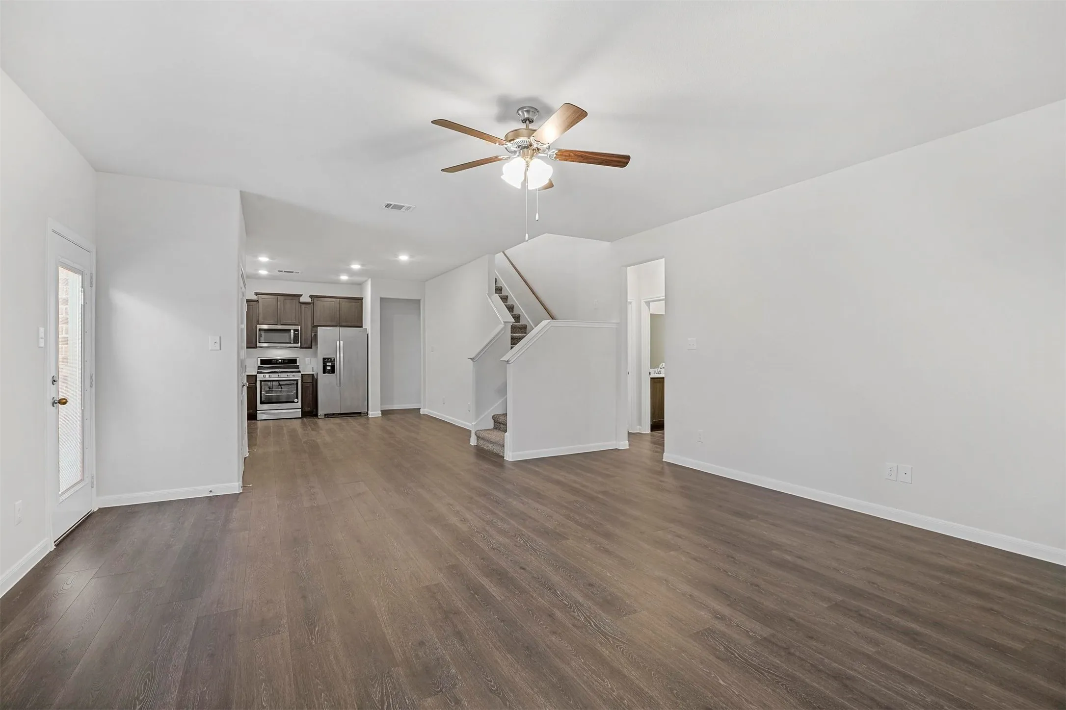 Wood-finish flooring throughout, ceiling fan with light fixture, recessed lighting, and kitchen with stainless steel appliances