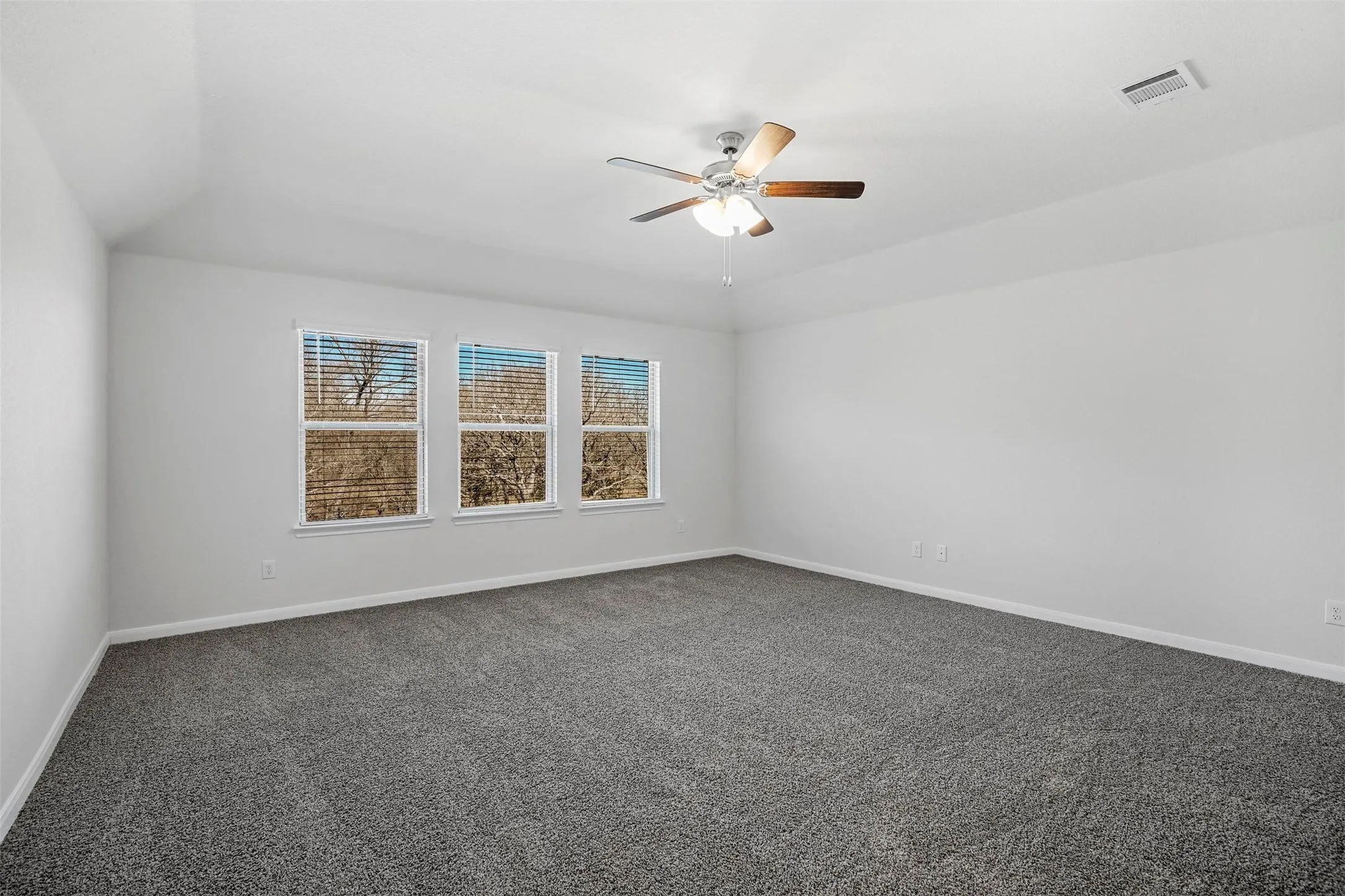 Bright and spacious bedroom flooded with natural light through three large double-hung windows
