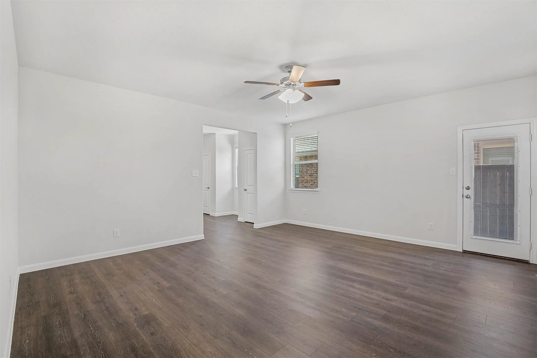 Spacious room featuring wood-finish flooring, a ceiling fan, and a window providing natural light