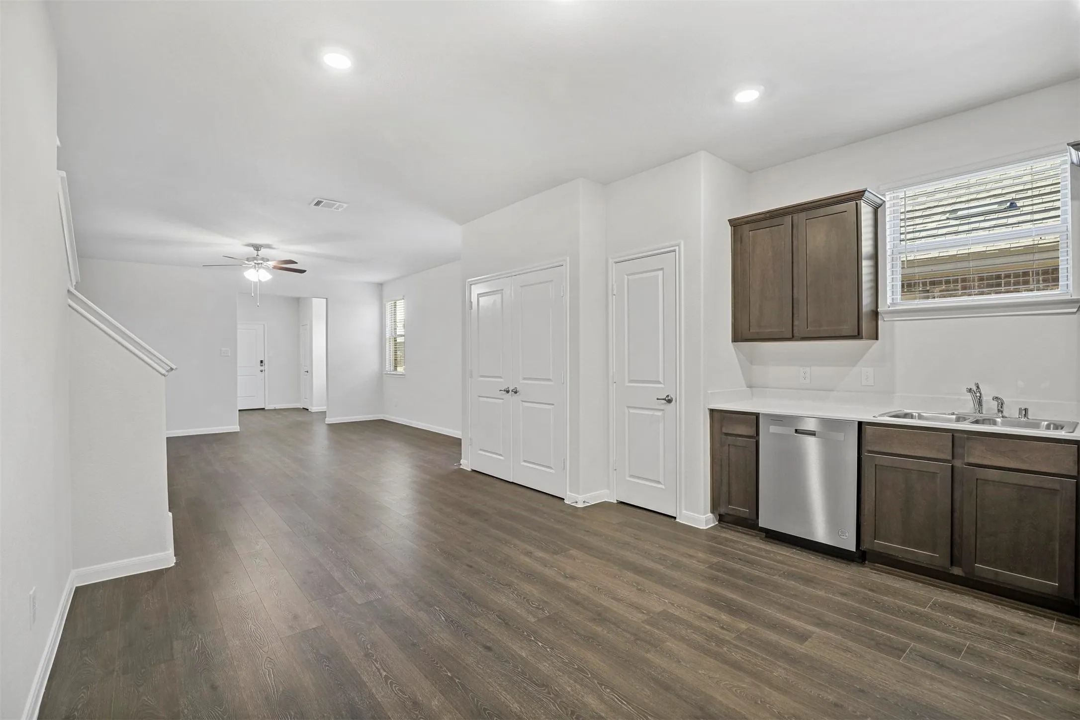 Wood-finish flooring throughout, recessed lighting, ceiling fan, dark wood cabinetry, and stainless steel dishwasher