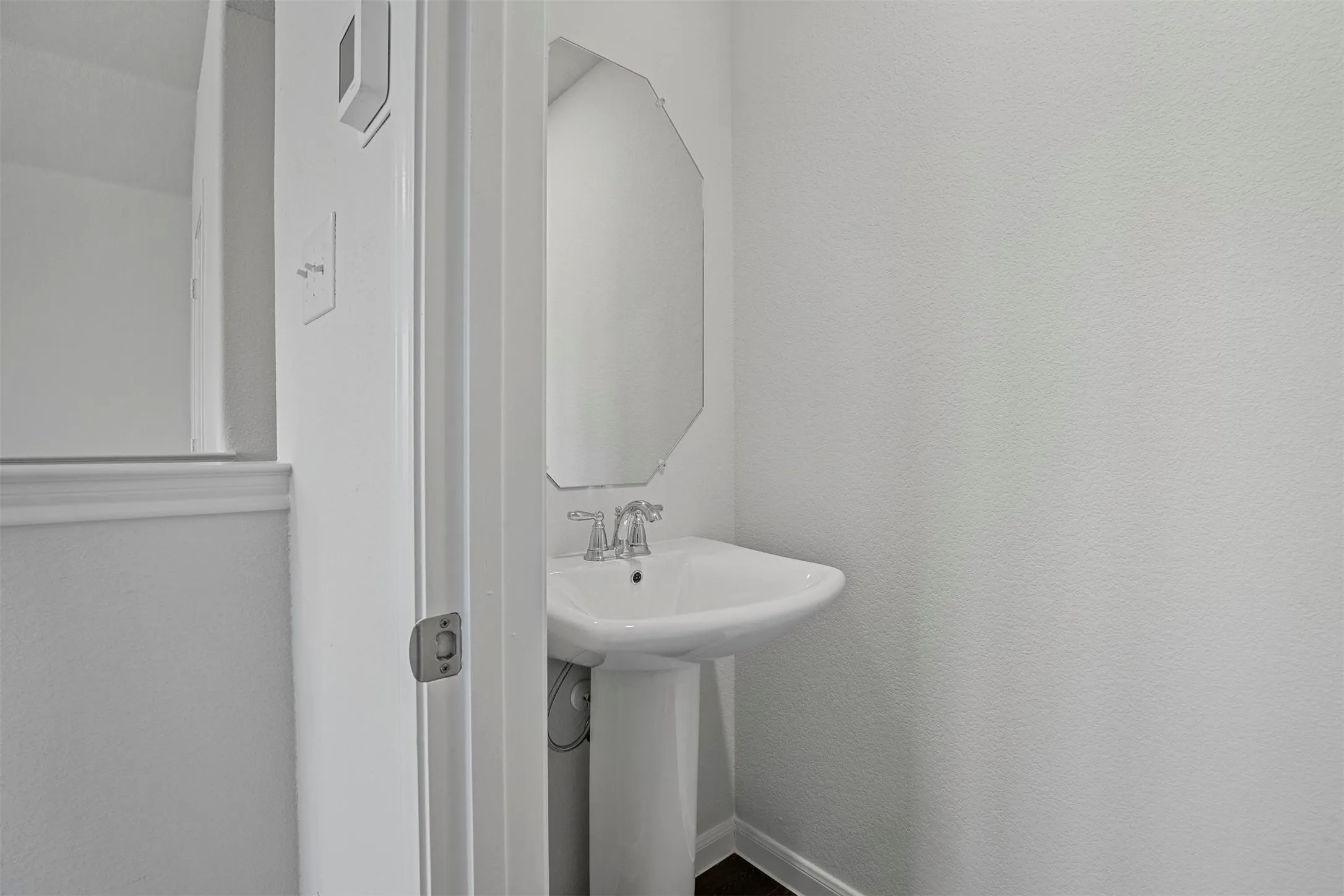 Pedestal sink with chrome faucet and an ornate wall-mounted mirror
