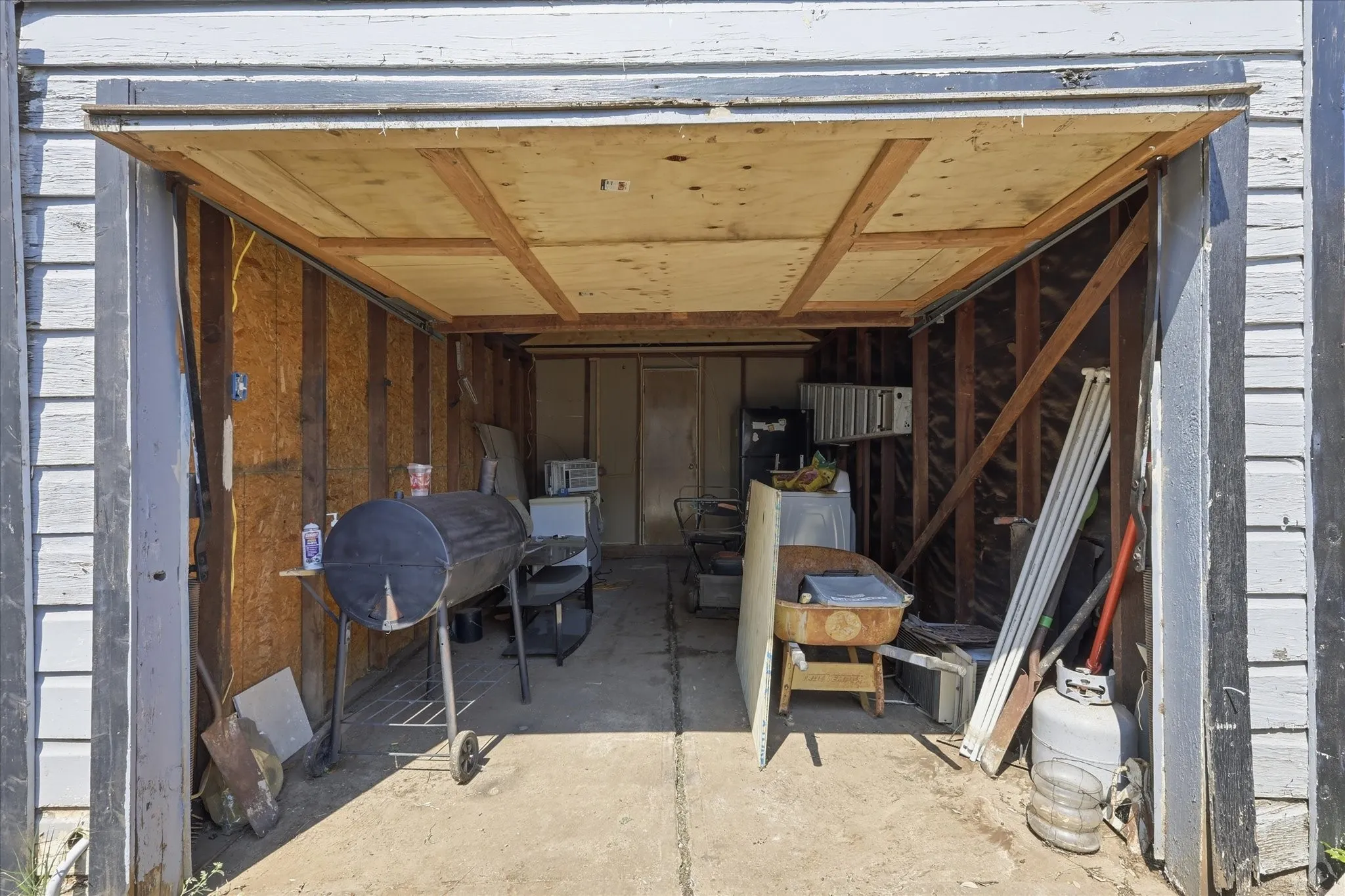 Interior garage view showing a concrete floor, exposed framing, overhead door, and flexible storage space. This area offers practical utility for tools, lawn equipment, bikes, seasonal items, hobbies, or workshop use, adding functional value beyond the home’s interior living space.
