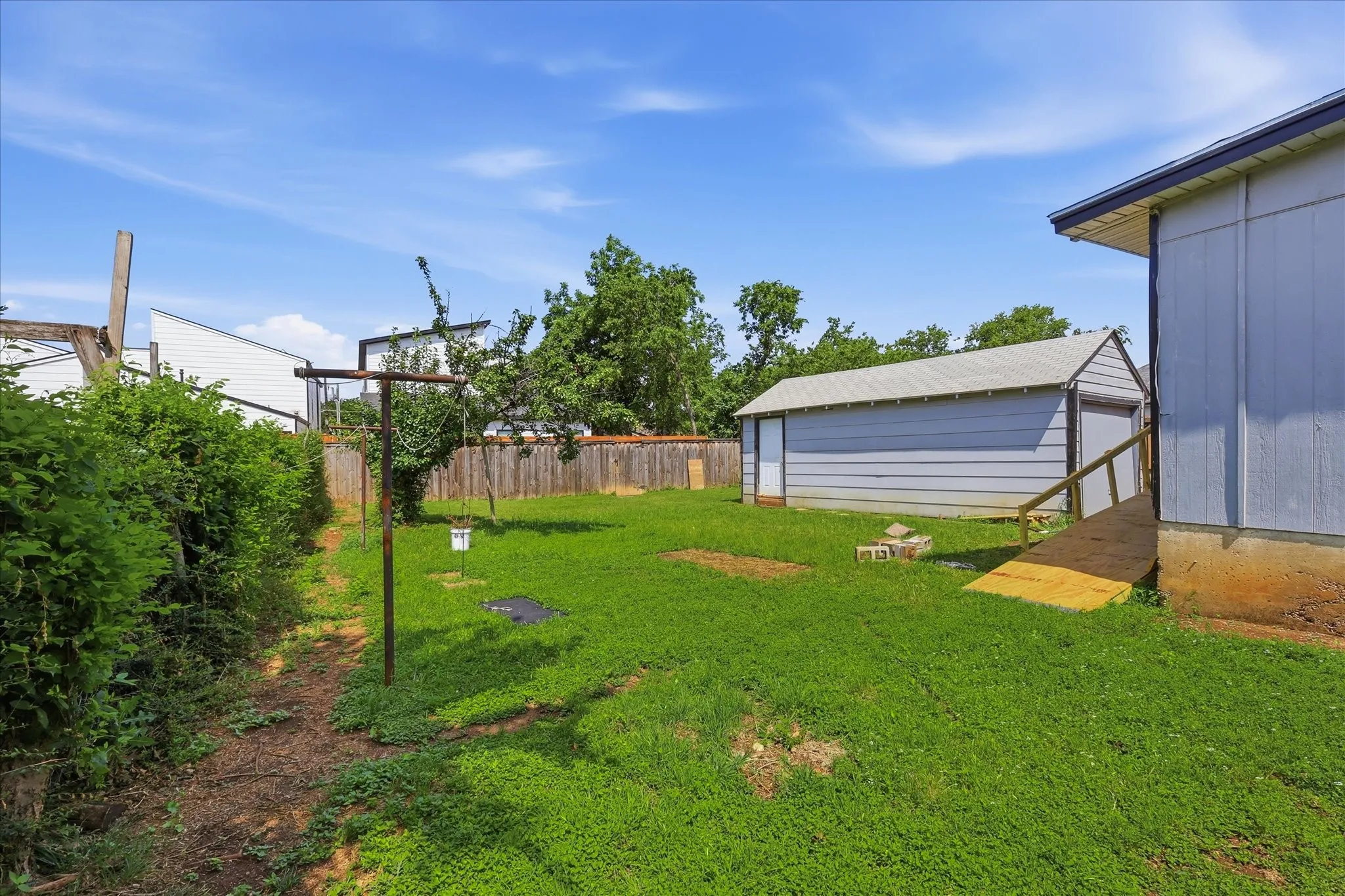 Detached garage exterior with side-entry door and generous lawn space surrounding it. This structure adds valuable flexibility for parking, storage, tools, lawn equipment, hobbies, or workshop use, while its placement within the backyard keeps the main outdoor area open and functional.