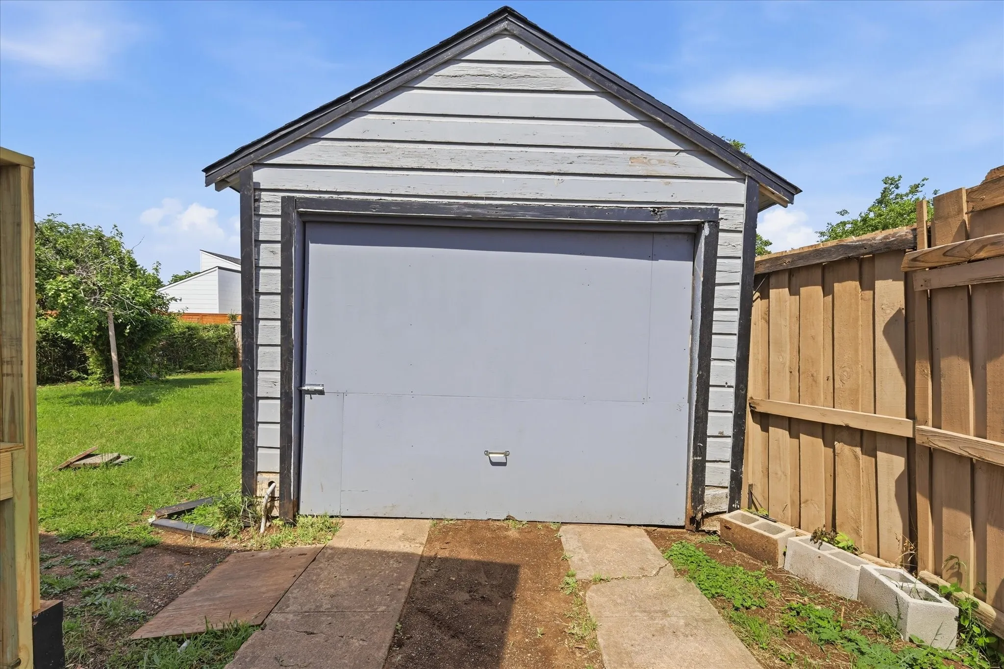 Detached garage view with driveway-style approach, fenced side area, and access into the backyard. This structure provides valuable utility for parking, storage, tools, hobbies, or workshop potential. The garage adds a major functional advantage to the property, especially for buyers who need extra space beyond the home’s interior square footage.