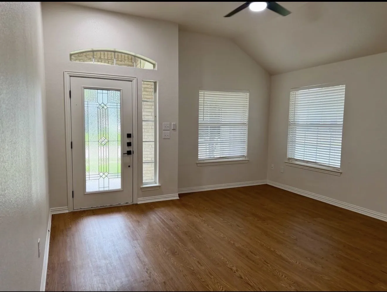 Bright foyer with elegant glass-paneled entry door featuring decorative beveled detailing, transom window above, and sidelite