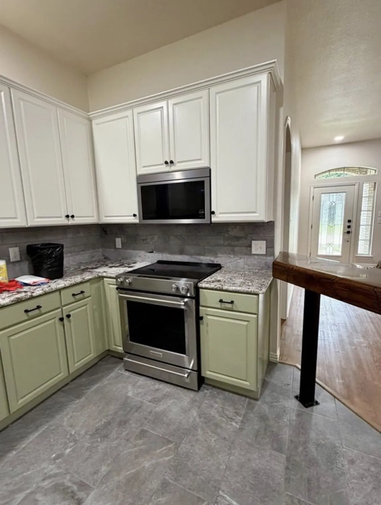 Kitchen featuring stainless steel range, stainless steel microwave, stone countertops, and two-tone cabinetry with black hardware