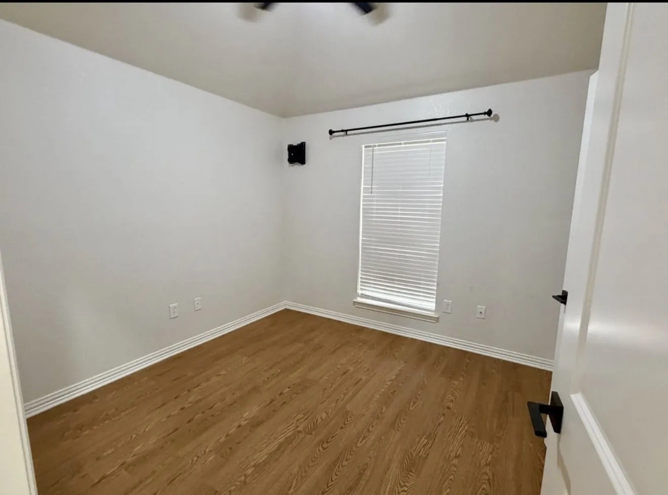 Wood-finish flooring, white walls, and a window with blinds