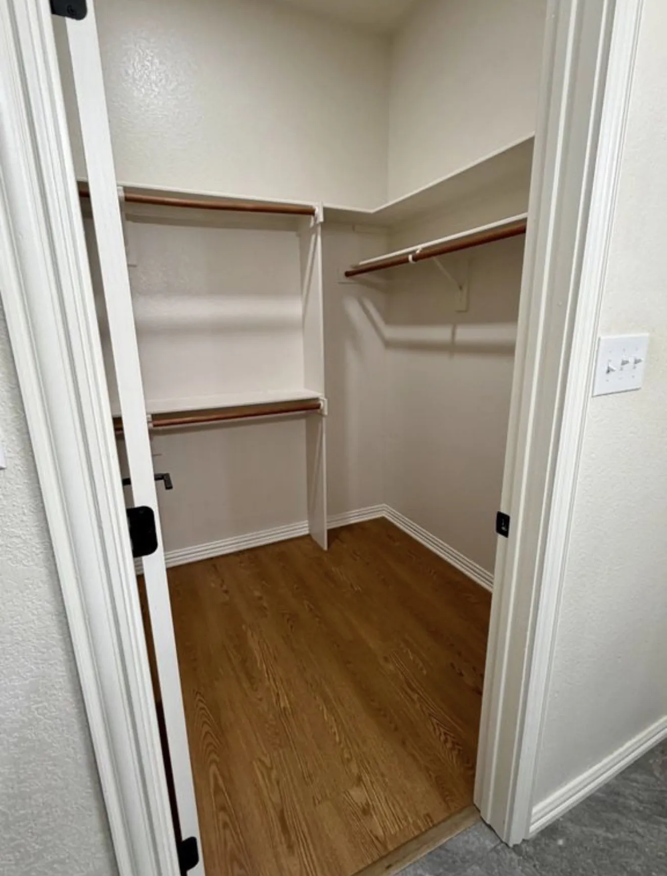 Walk-in closet featuring wood-finish flooring, multiple shelving units, and clothing rods