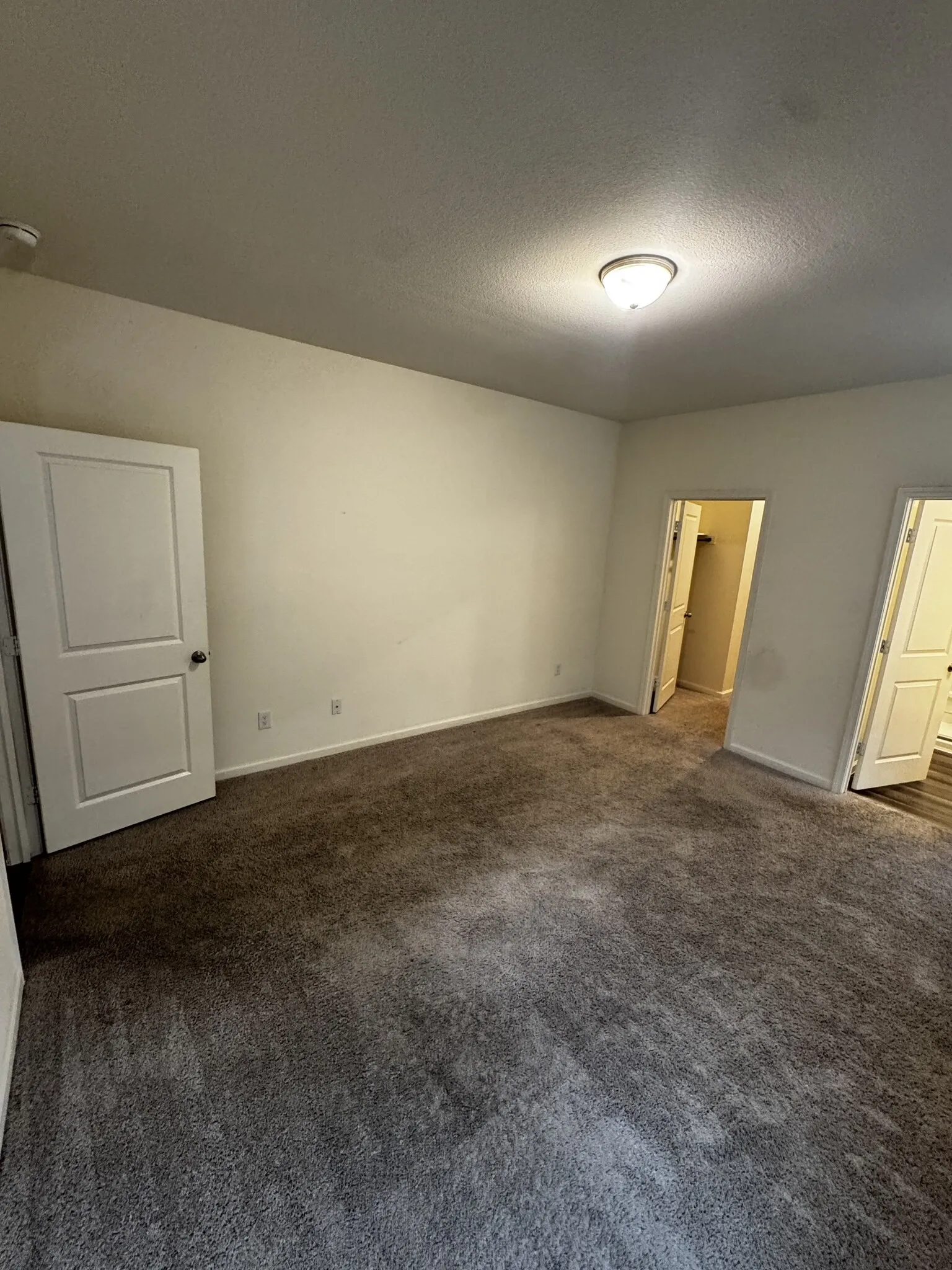 Recessed ceiling light fixture, white interior doors, and textured wall finish