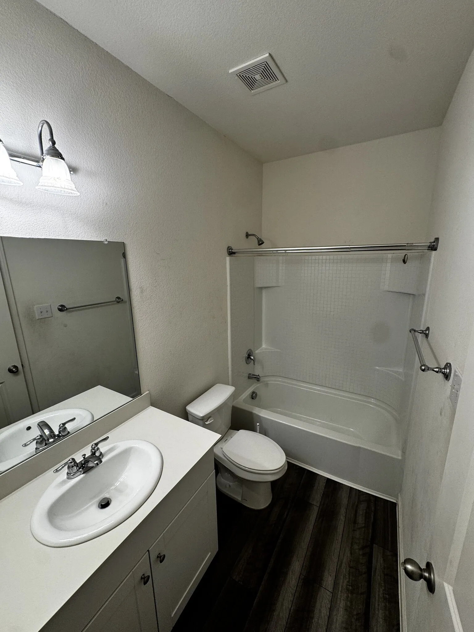 White vanity with integrated sink, chrome faucet, and dark wood-finish flooring