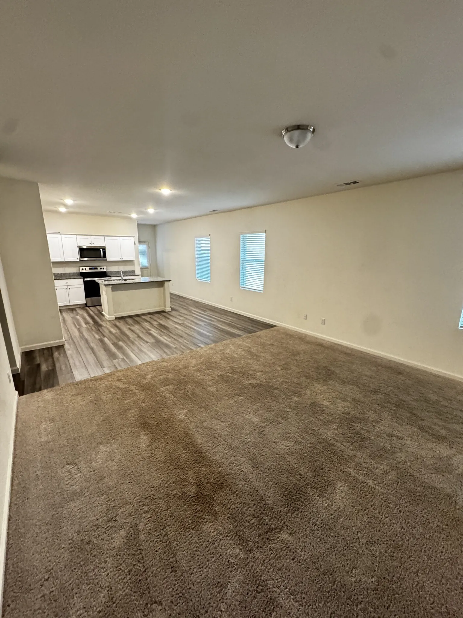Open-concept living area with neutral carpeting