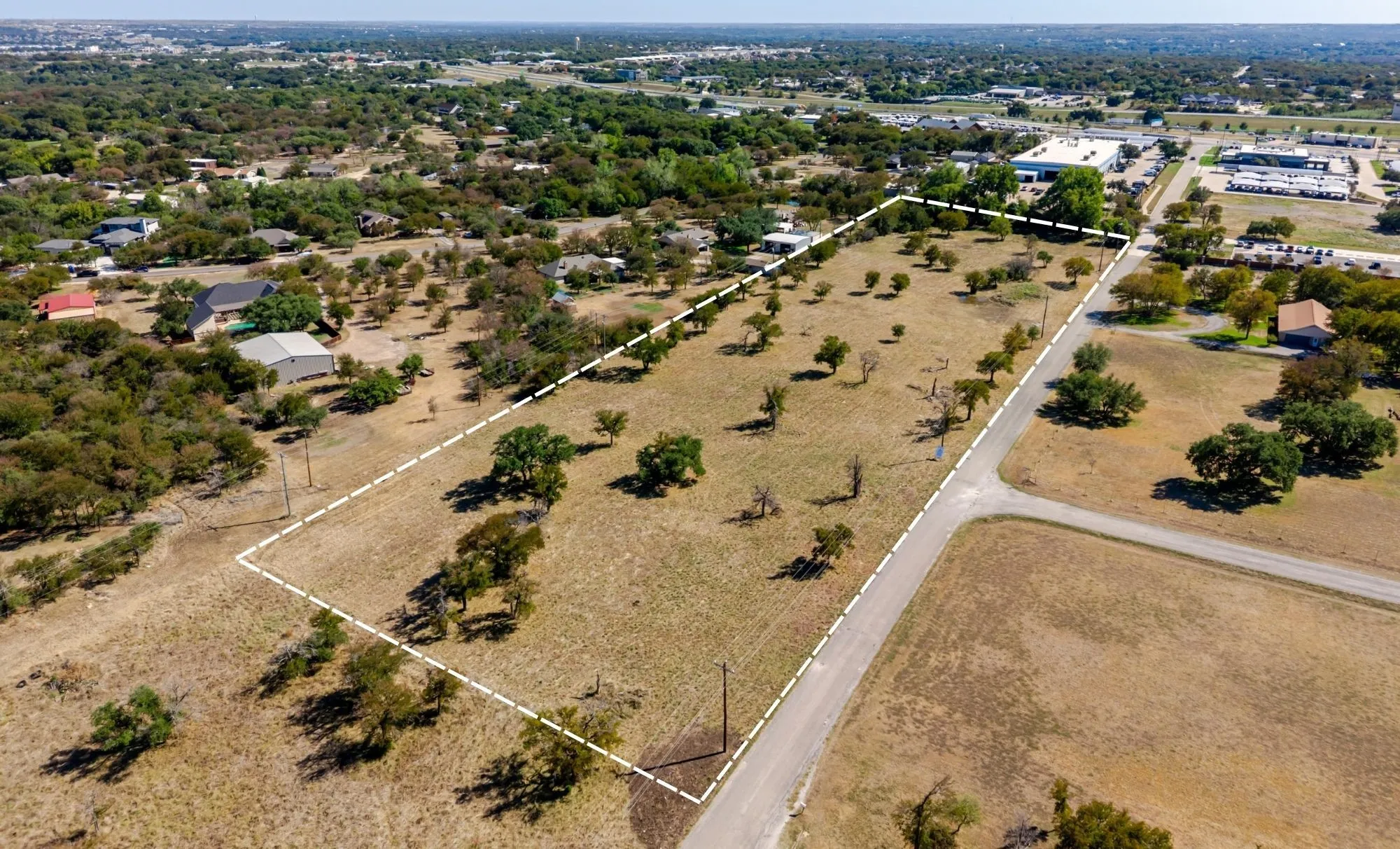 Expansive land parcel with scattered mature trees and direct road frontage