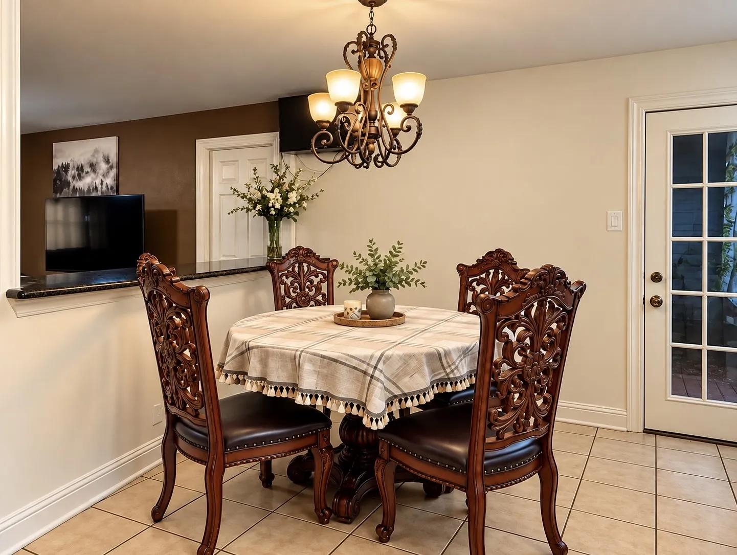 Tiled flooring, overhead chandelier, half-wall with a dark countertop, and a glass-paneled exterior door