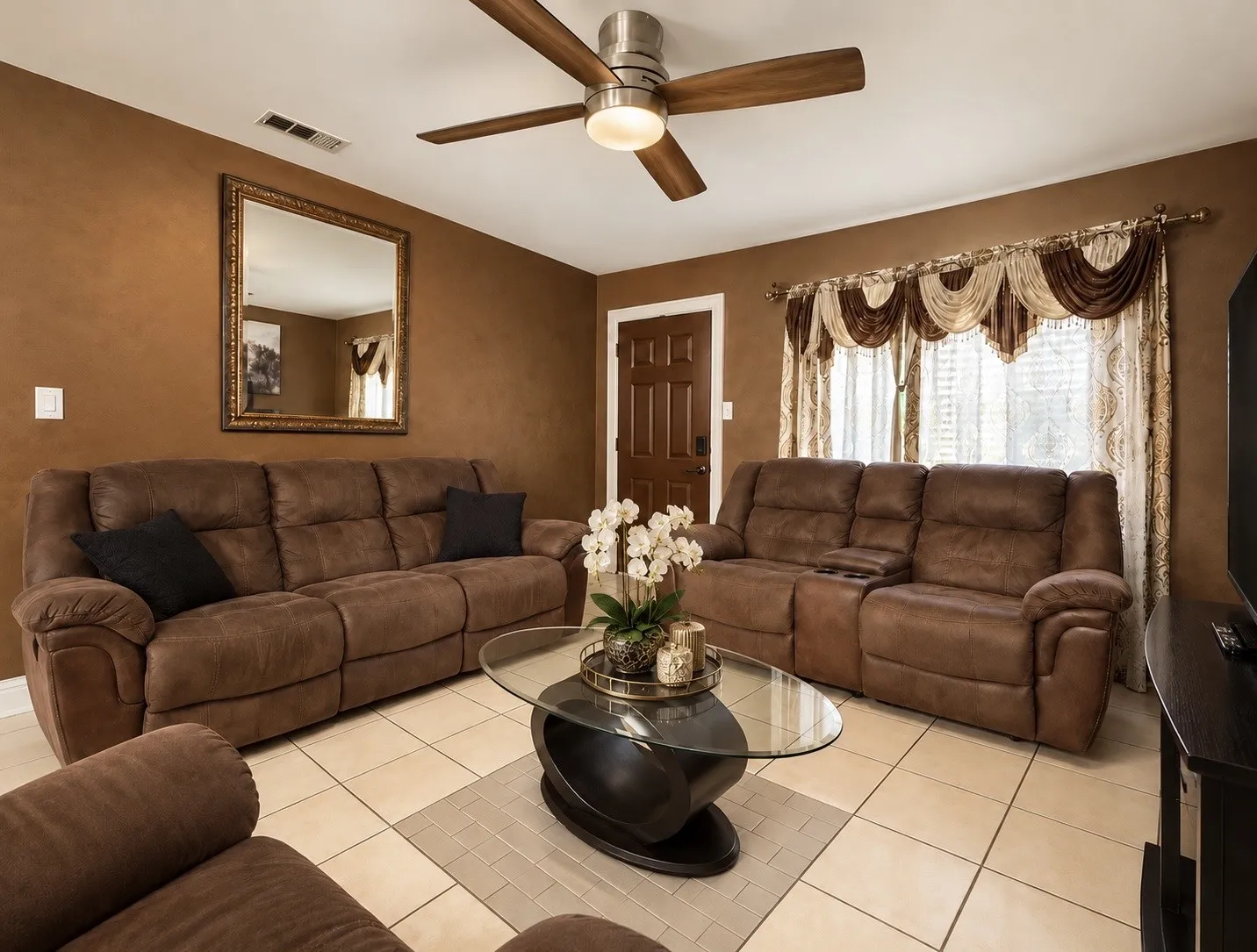 Ceiling fan with integrated lighting, tiled flooring, front door with panel detailing, and a prominent window