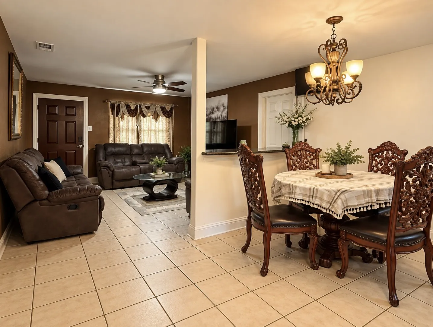 Open concept living space with tile flooring, a decorative chandelier, and a ceiling fan