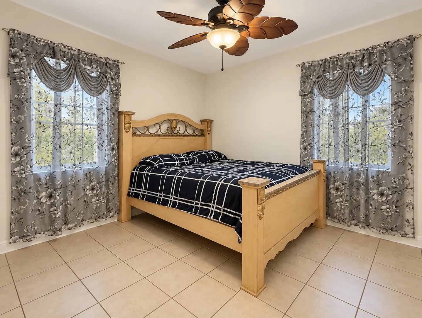 Room featuring tiled flooring, a ceiling fan with light fixture, and two windows