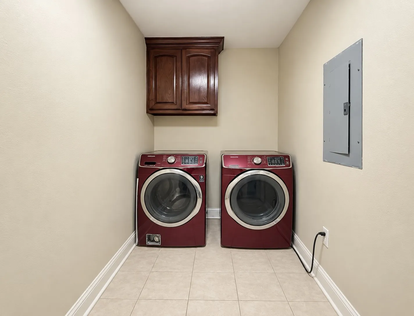 Laundry area featuring a built-in wood-finish cabinet and tile flooring