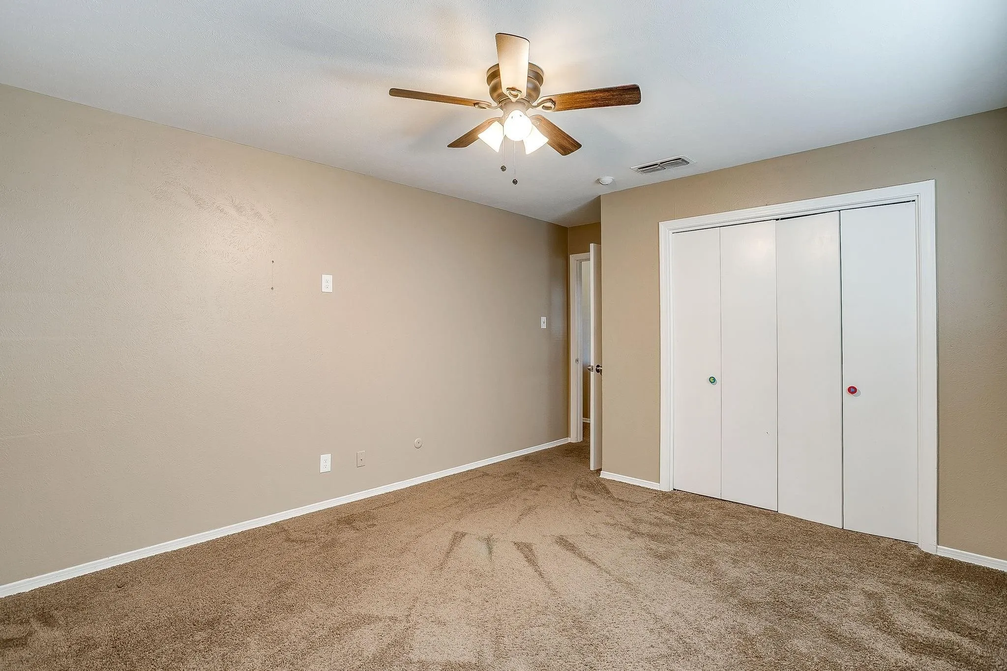 Neutral tone wall finishes, ceiling fan with integrated lighting, carpet flooring, and bi-fold closet doors